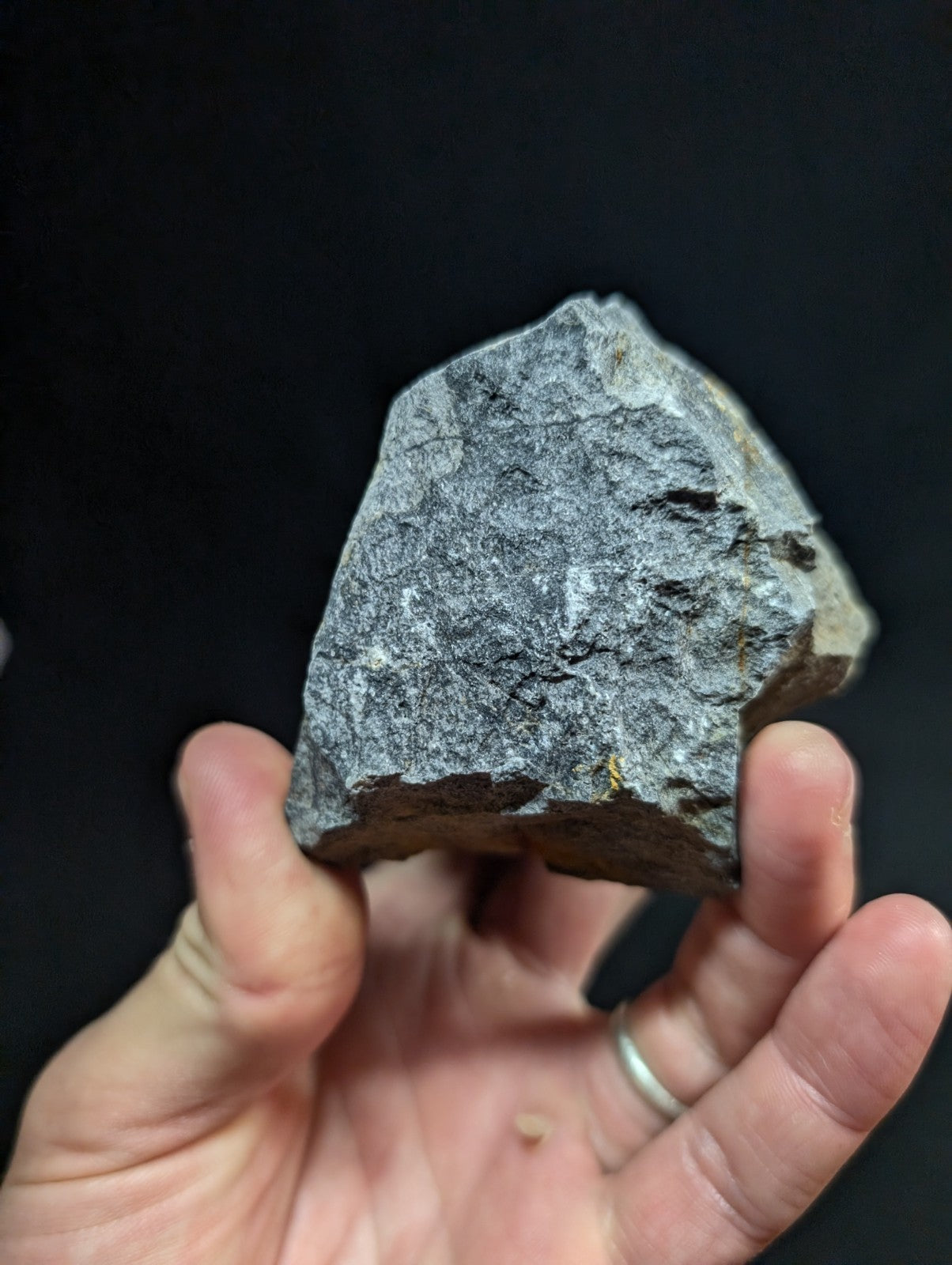 A rough, irregularly shaped gray rock with a textured surface and subtle darker patches.