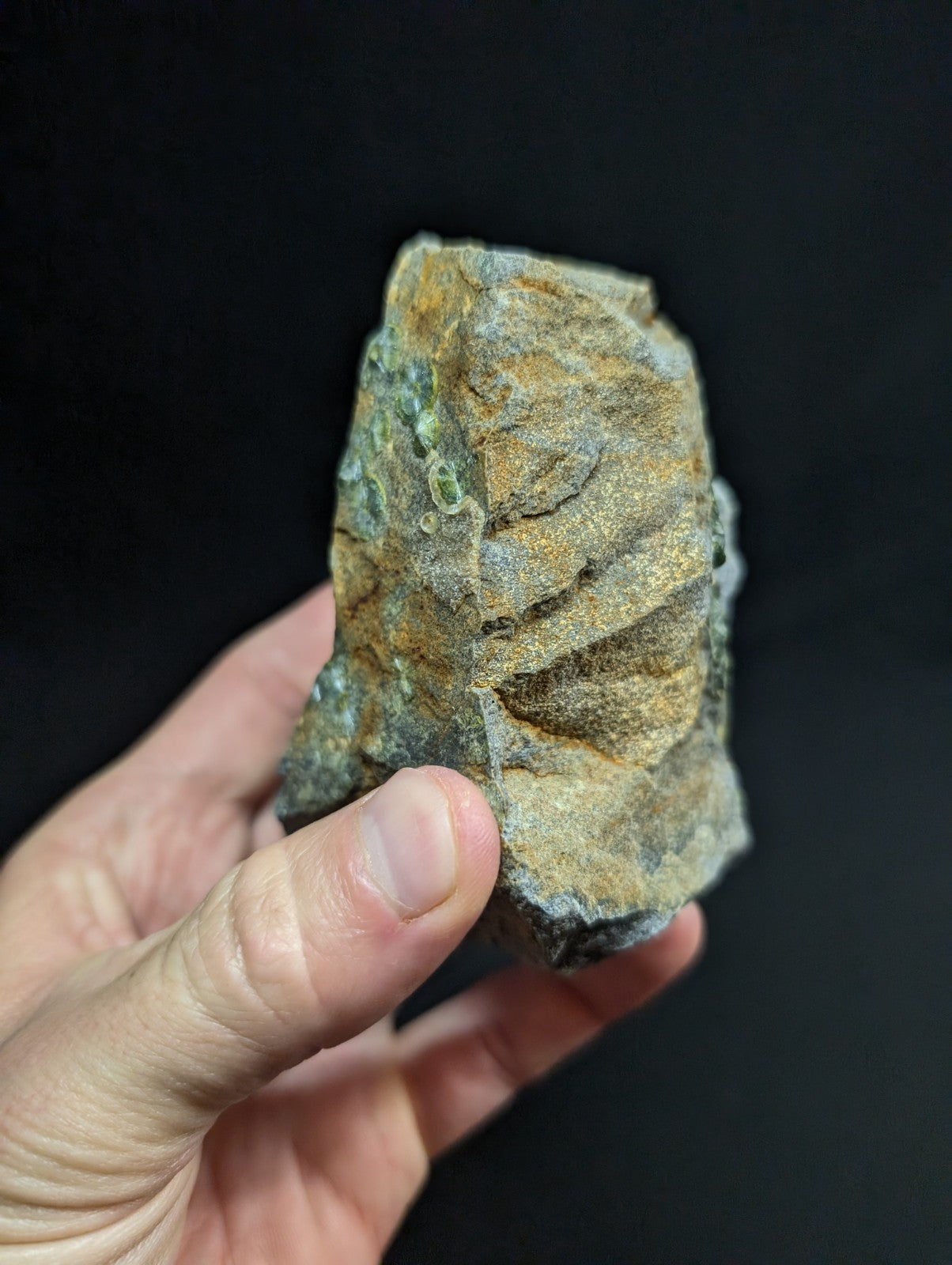 A rugged, irregularly shaped rock with a mottled surface of earthy brown and green hues.