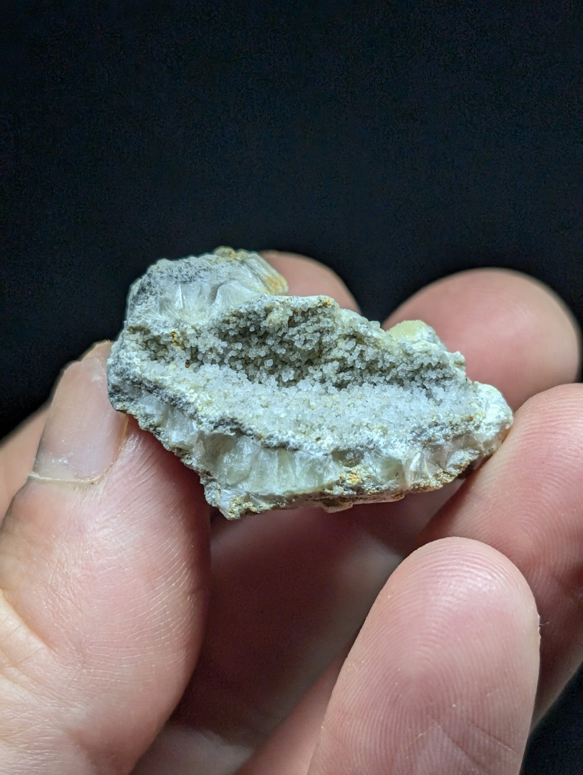 A rough, pale greenish-white mineral specimen with a crystalline texture and speckled surface.