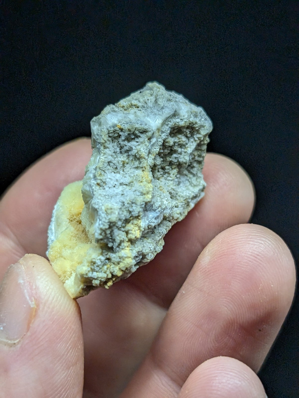 A rough, irregularly shaped mineral specimen with a mottled gray and yellow surface.