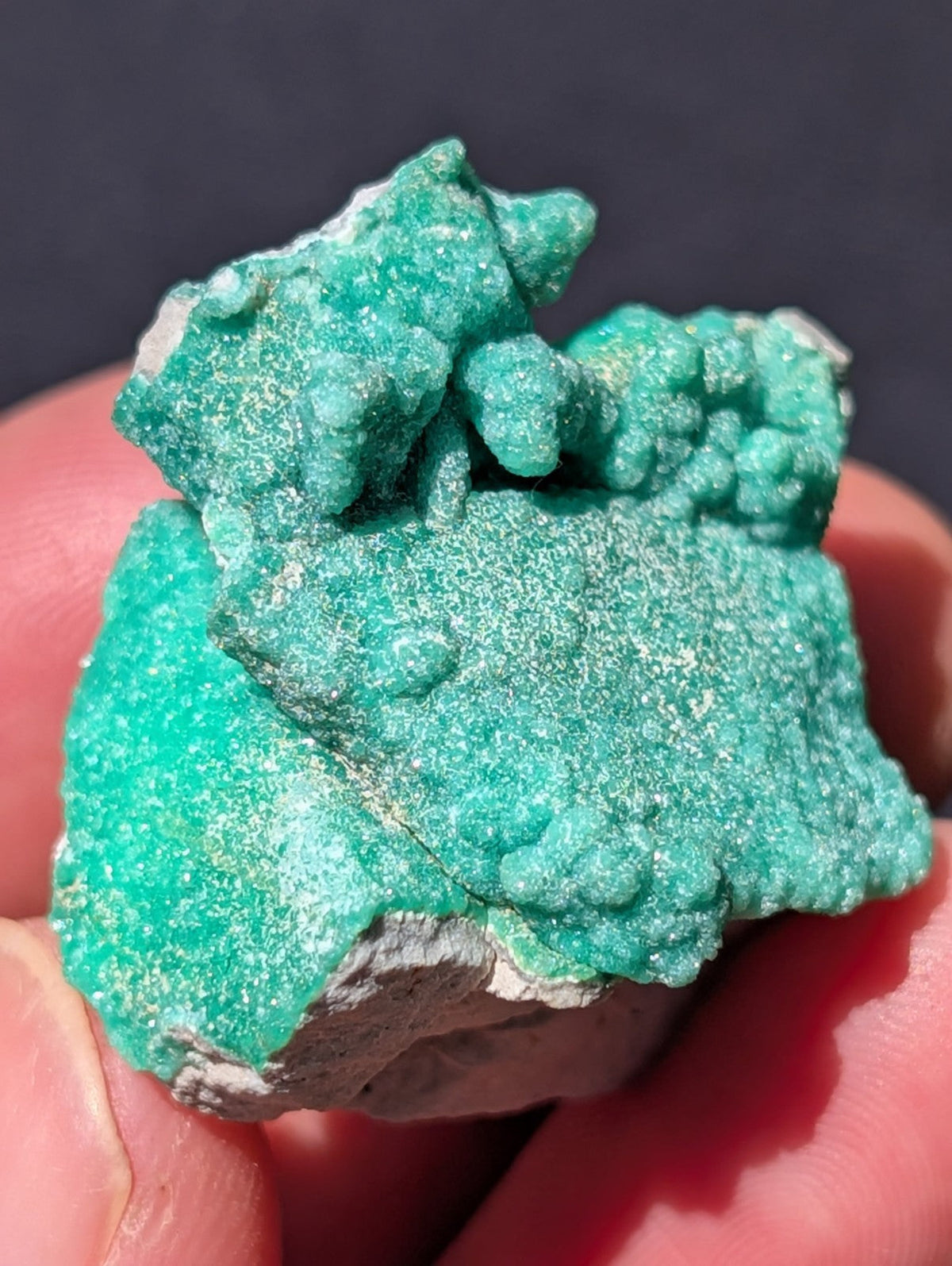 A vibrant turquoise-green mineral specimen with a rough, crystalline texture and white speckled surface.