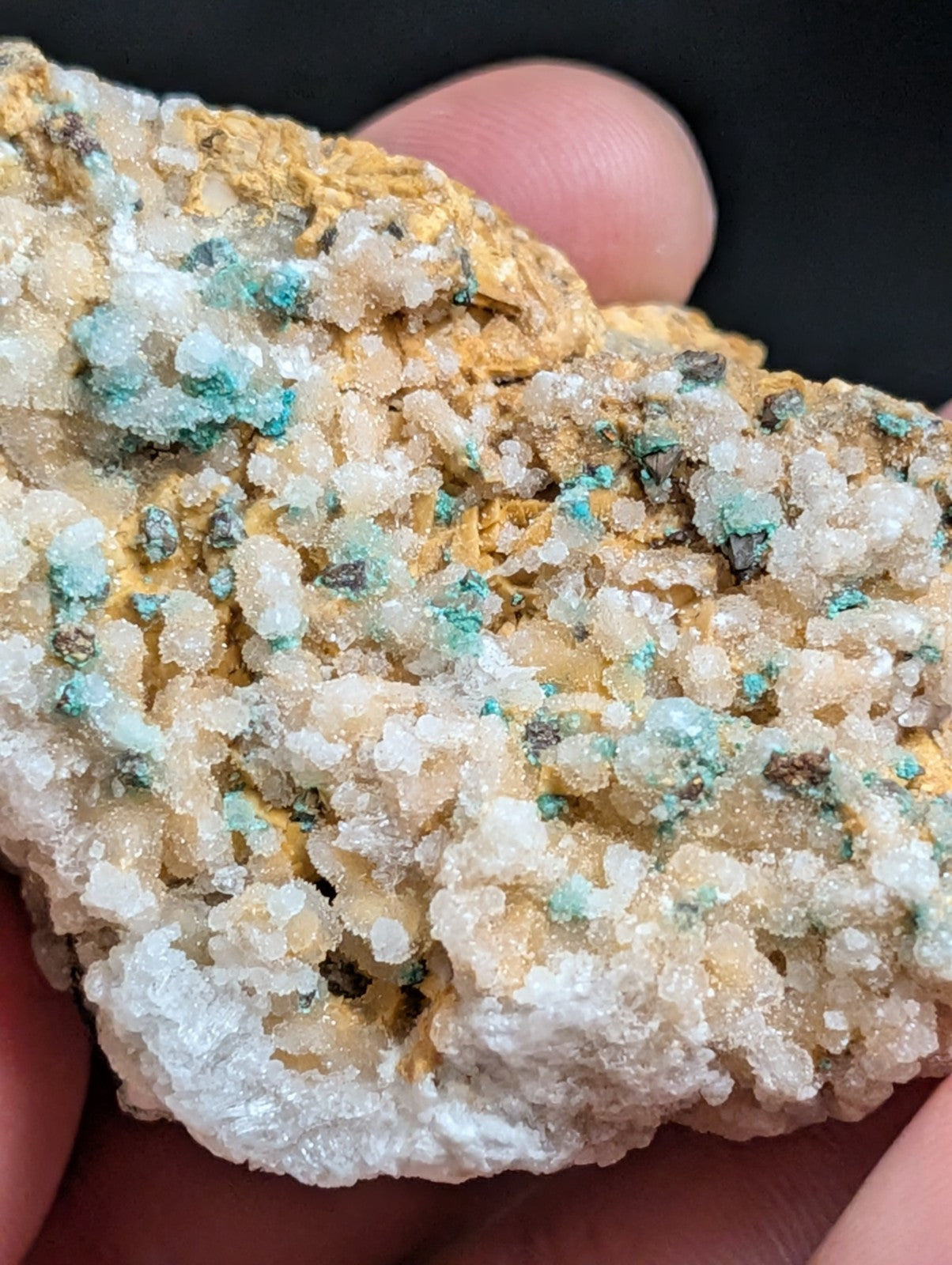 A textured mineral specimen featuring a mix of translucent white crystals, vibrant turquoise patches, and golden-yellow matrix.