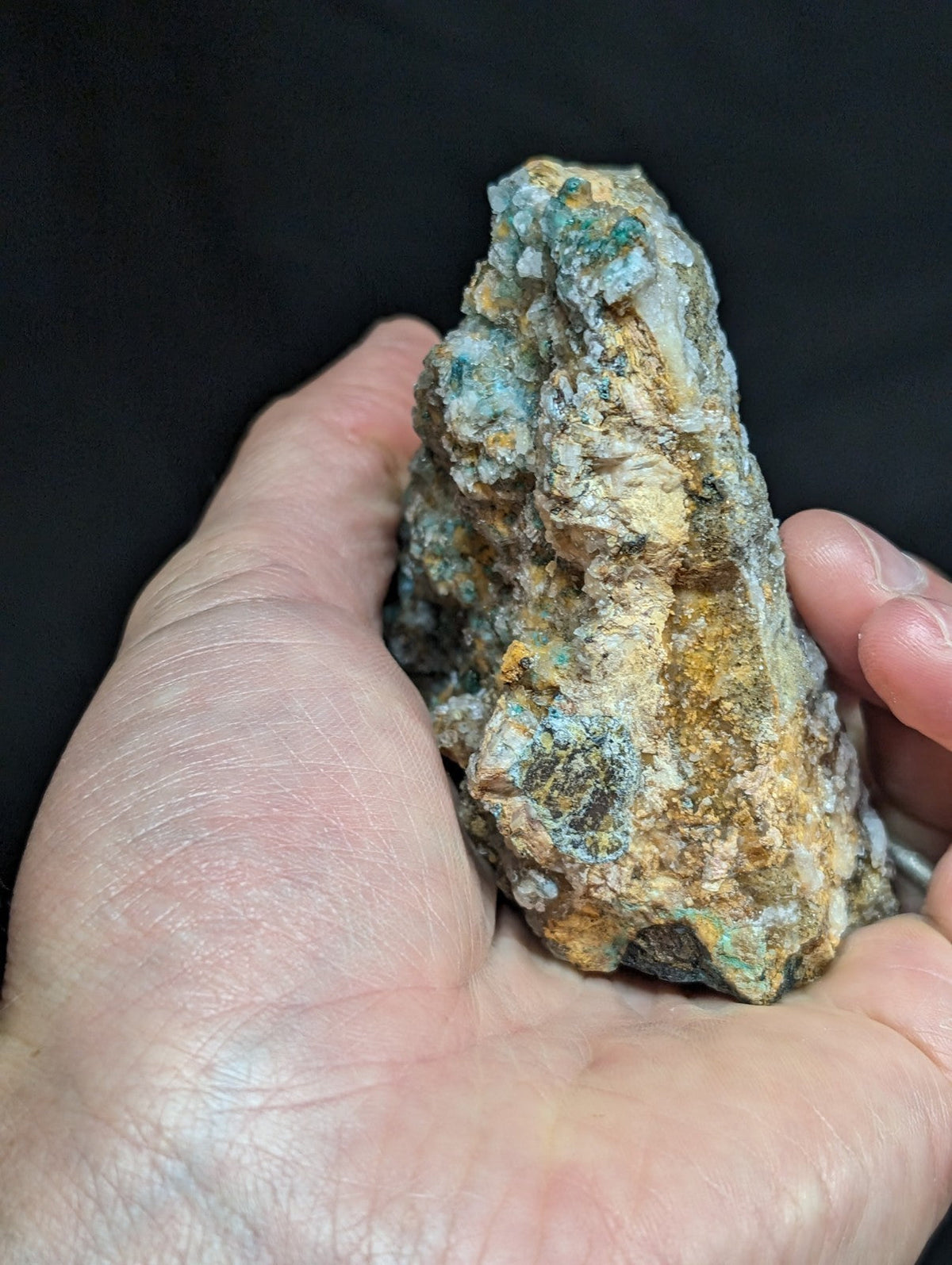 A rugged, irregularly shaped mineral specimen with patches of vibrant turquoise and earthy yellowish-brown hues.