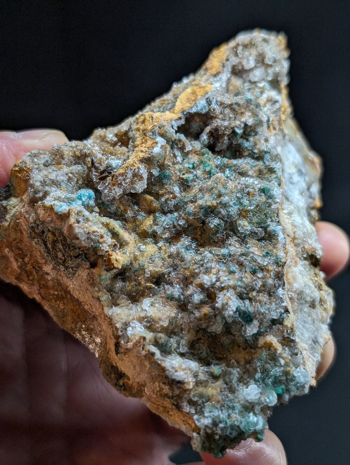 A rugged, irregularly shaped mineral specimen featuring a mix of earthy brown and gray tones with vibrant turquoise-green crystalline formations.