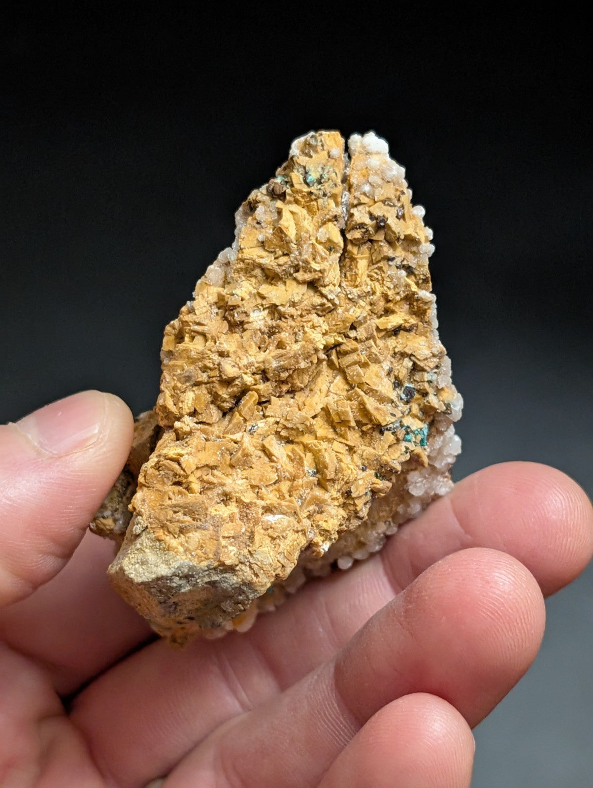 A textured, golden-yellow mineral specimen with crystalline formations and subtle green flecks.