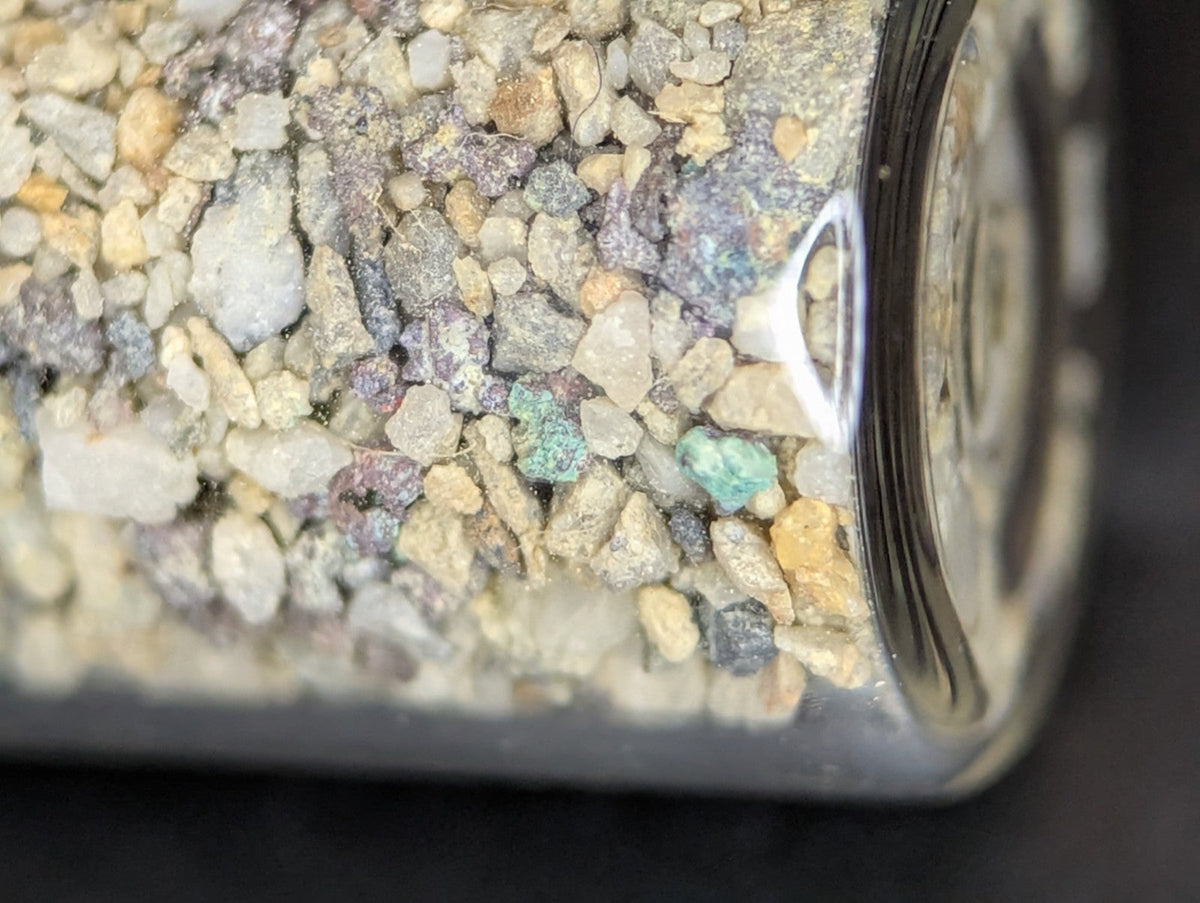 A clear glass jar filled with a mix of small, multicolored gravel stones.