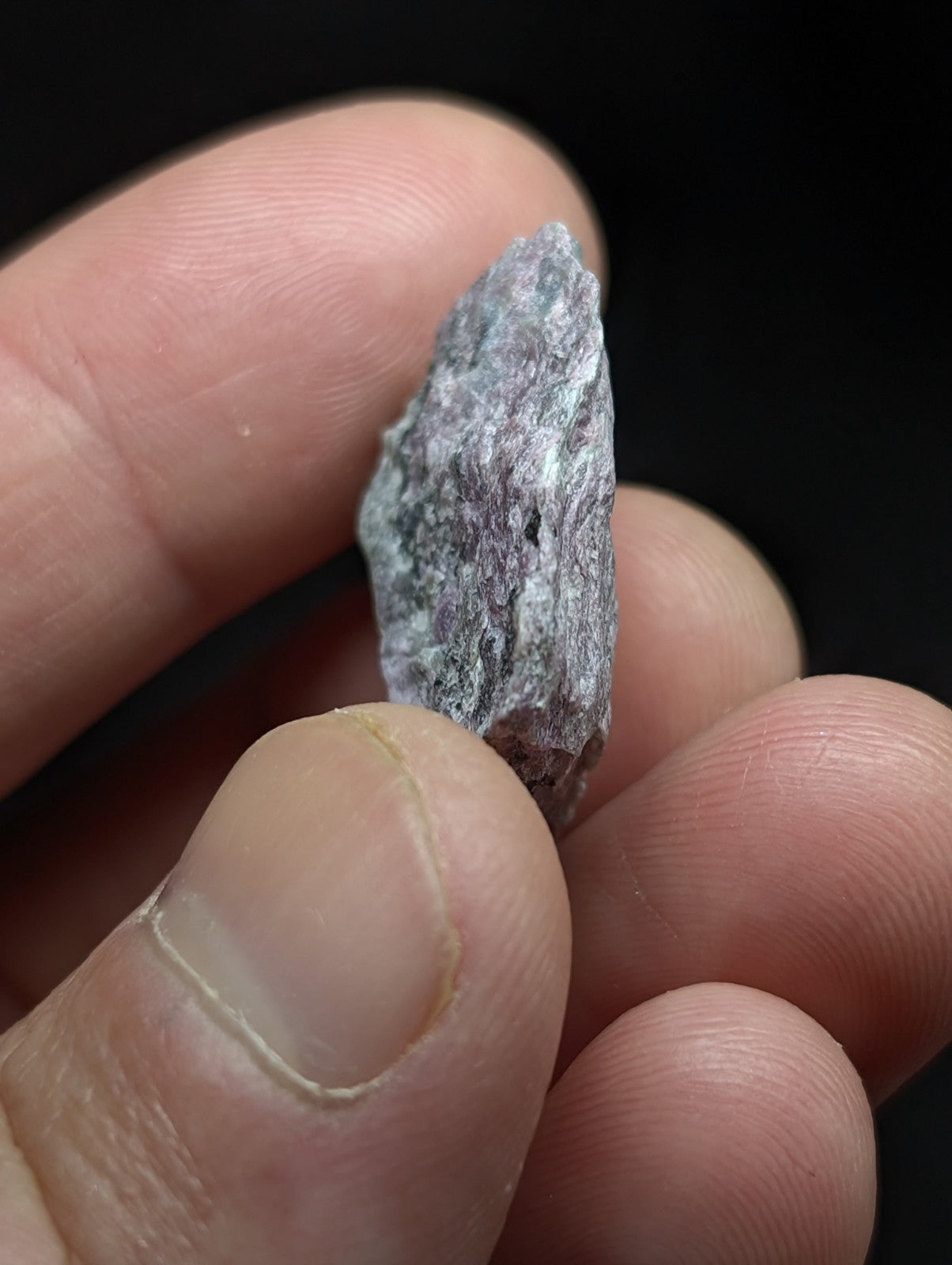 A rough, grayish stone with a textured surface and subtle greenish undertones.