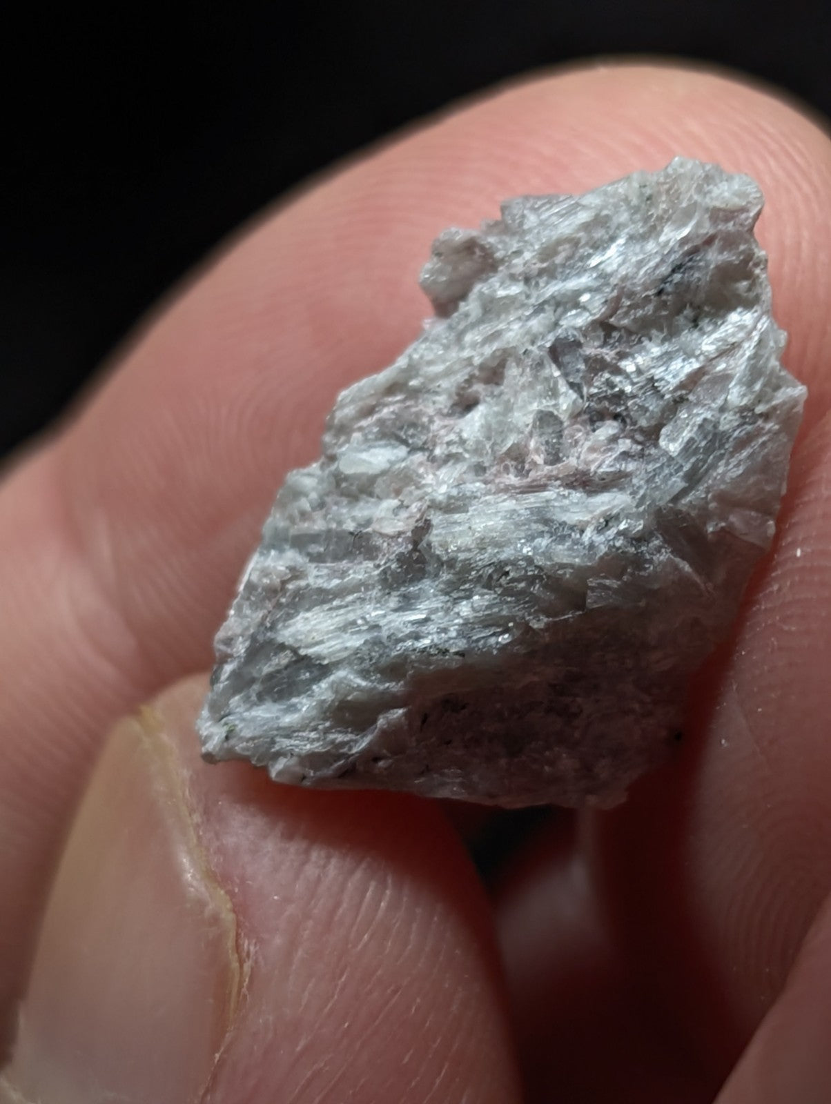 A rough, grayish-white mineral specimen with a crystalline texture and uneven surface.