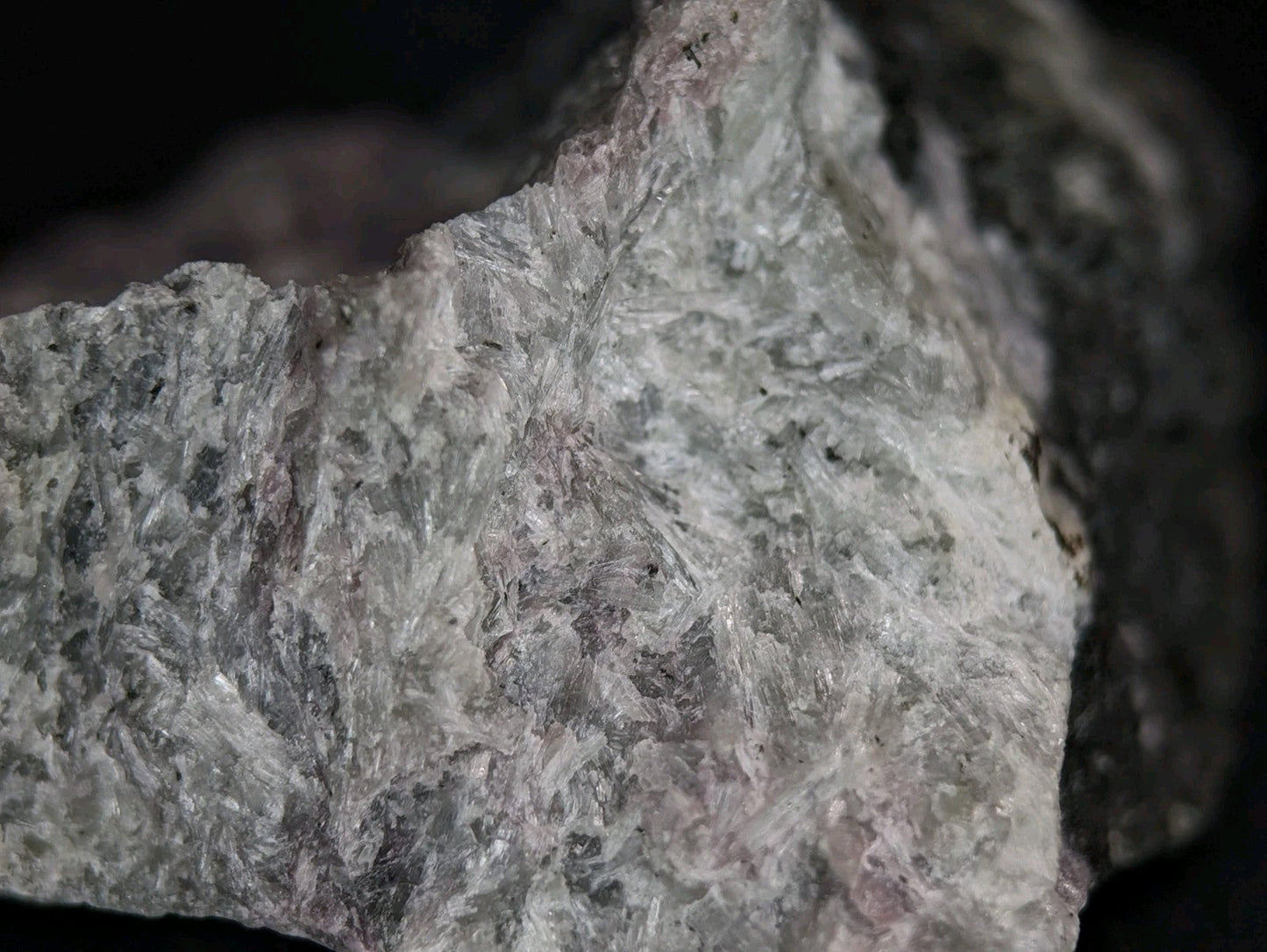 A rough, grayish-white rock with a crystalline texture and subtle pinkish undertones.