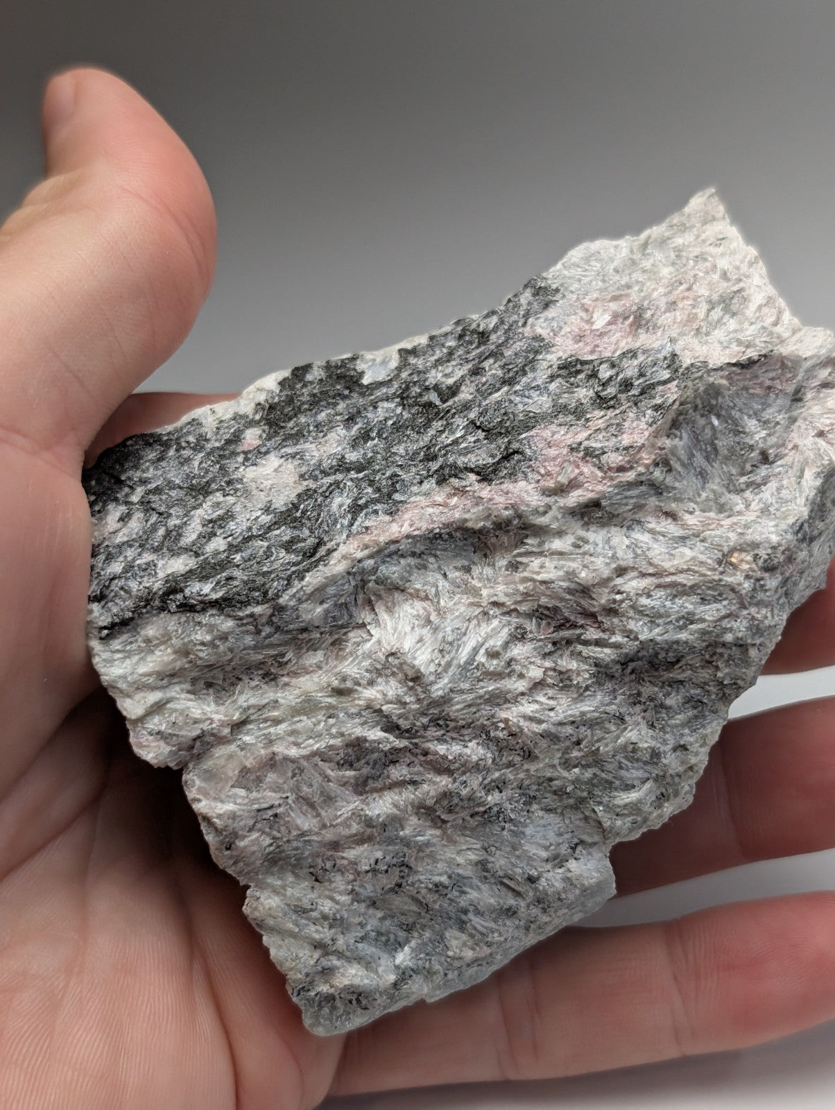 A rough miserite and wollastonite rock with mottled gray black and subtle pink hues from Wilson Springs Arkansas