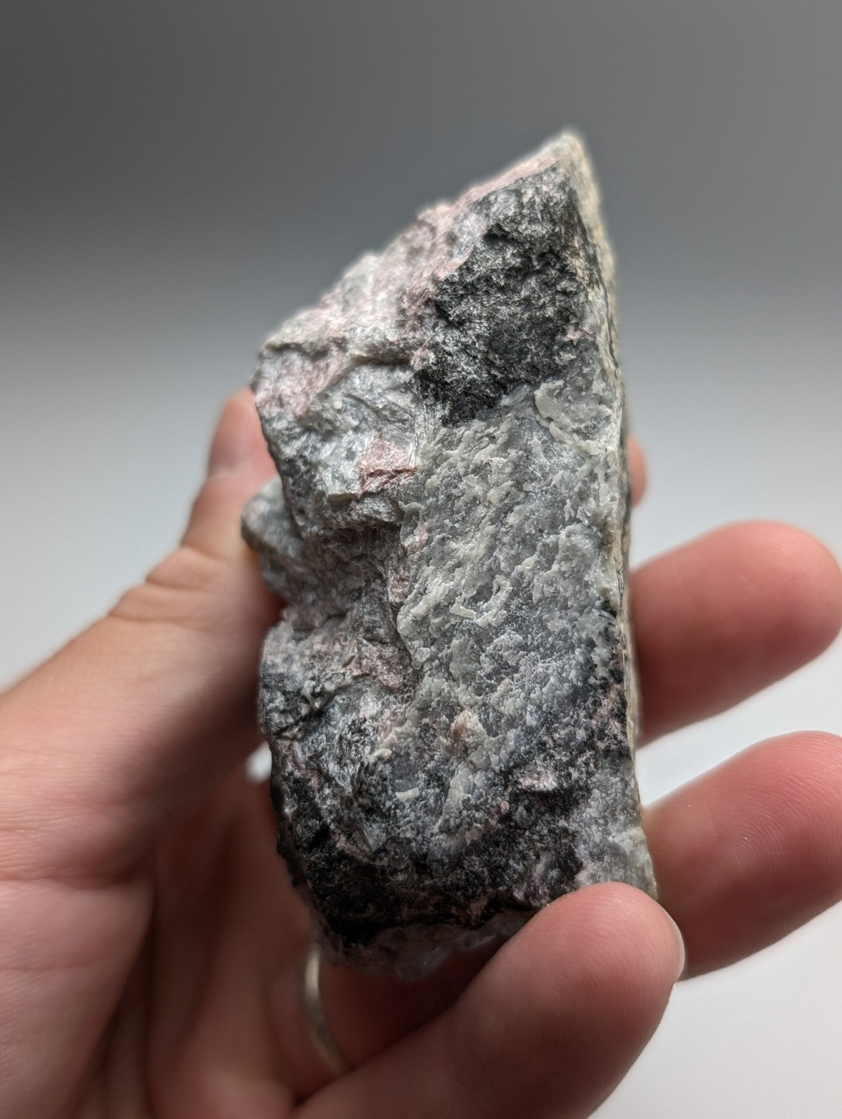 A rough gray miserite and wollastonite rock with pinkish and black mineral inclusions from wilson springs arkansas