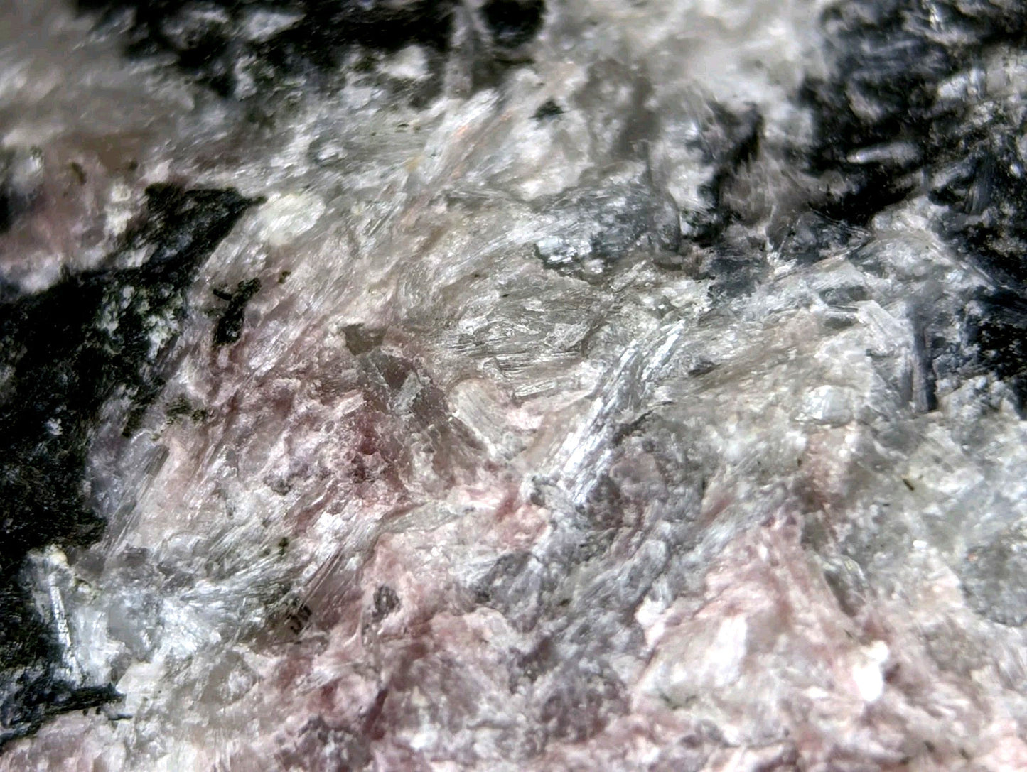 A textured mineral specimen with a mottled pattern of translucent white, gray, and dark black patches.