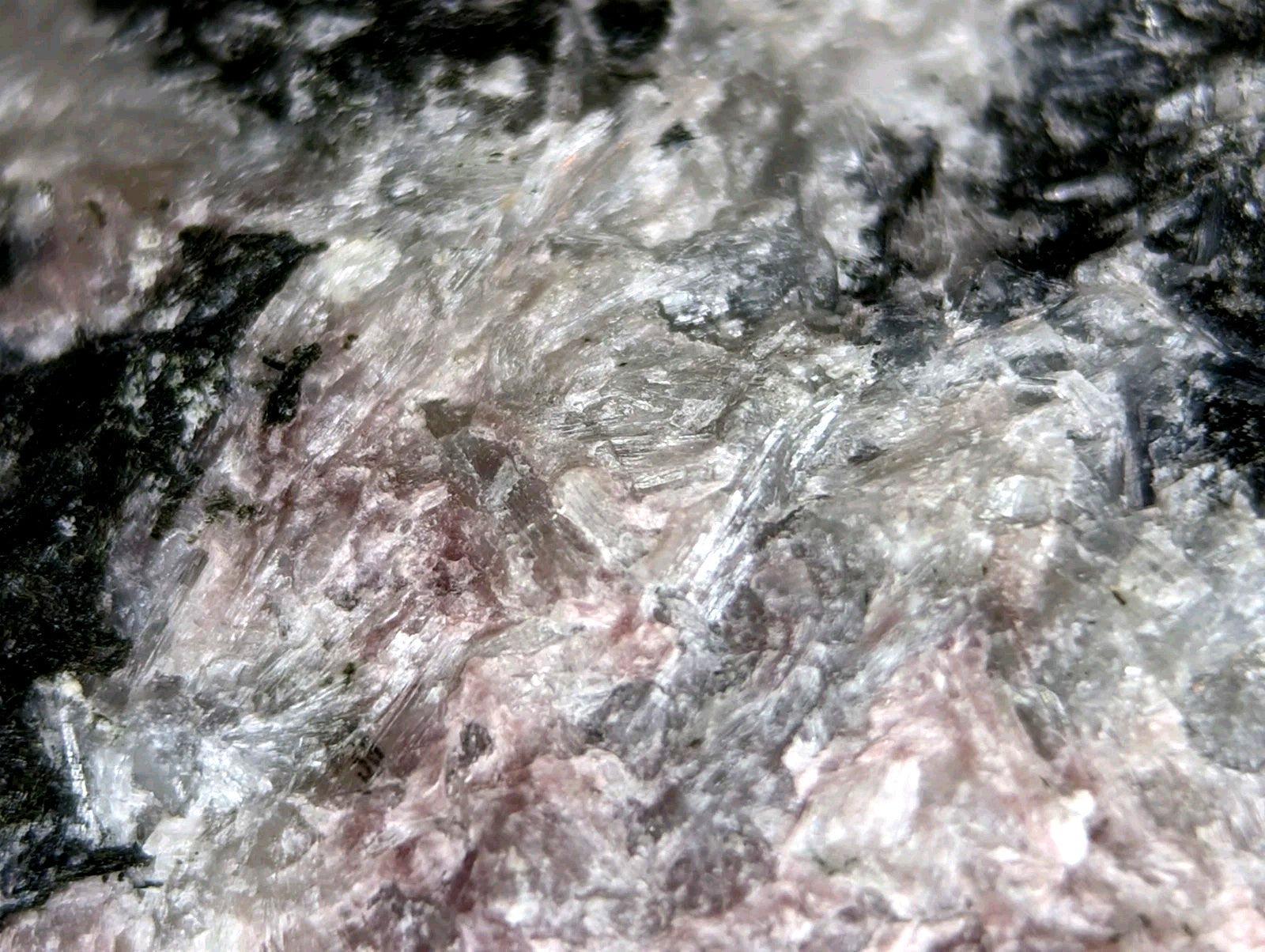 A textured mineral specimen with a mottled pattern of translucent white, gray, and dark black patches.