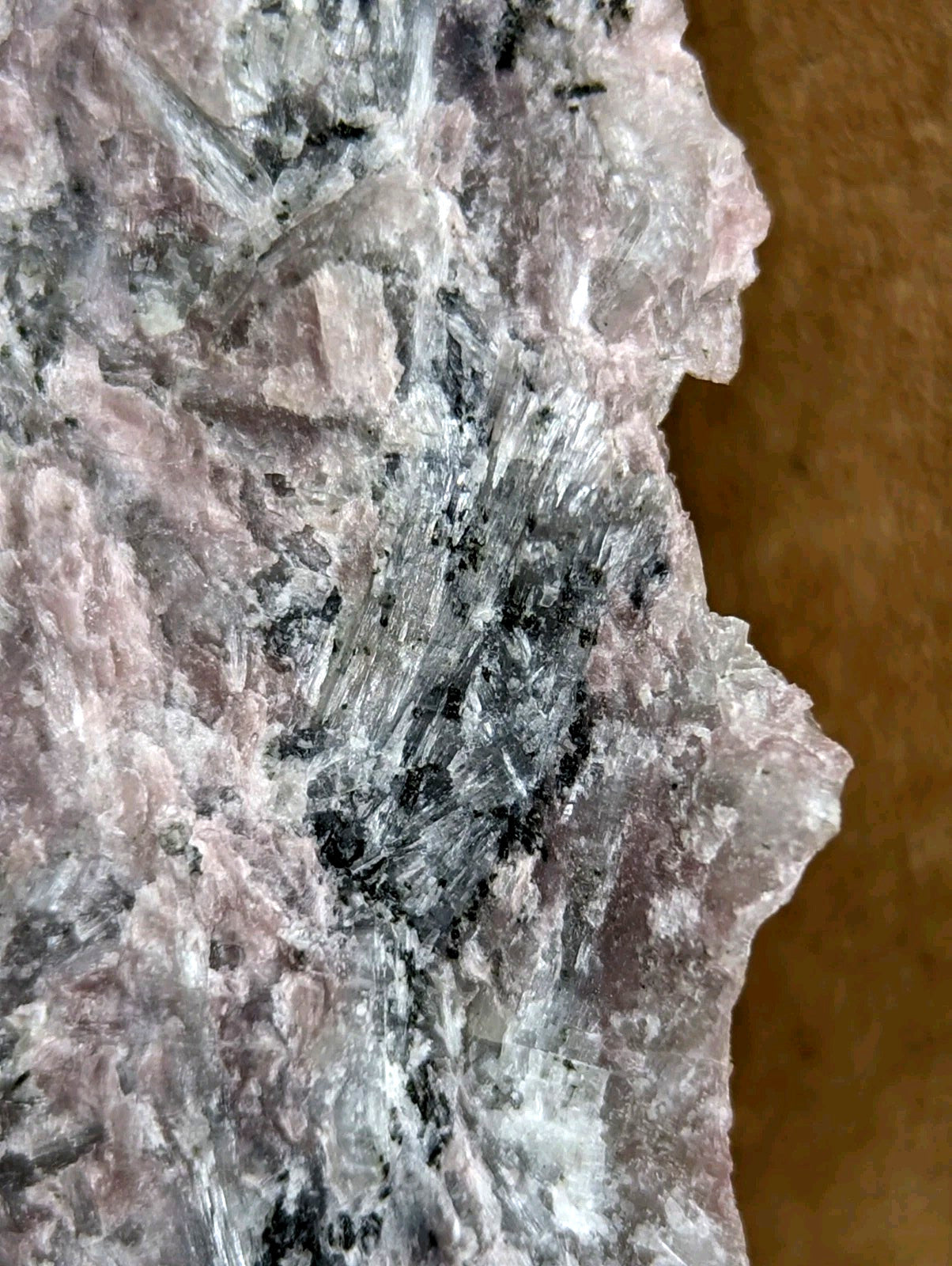 A rough, pinkish-gray mineral specimen with translucent crystalline formations and dark inclusions.