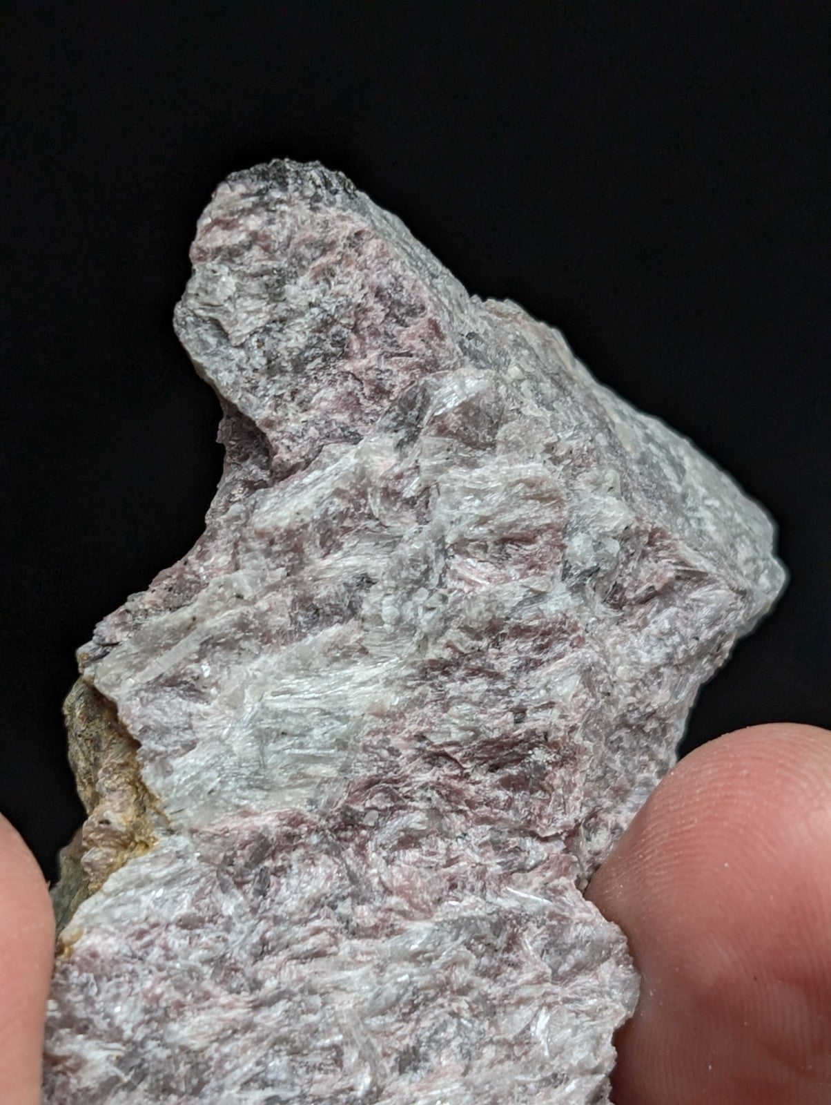 A rough, irregularly shaped mineral specimen with a mottled gray and pale pinkish hue, displaying visible crystalline textures.