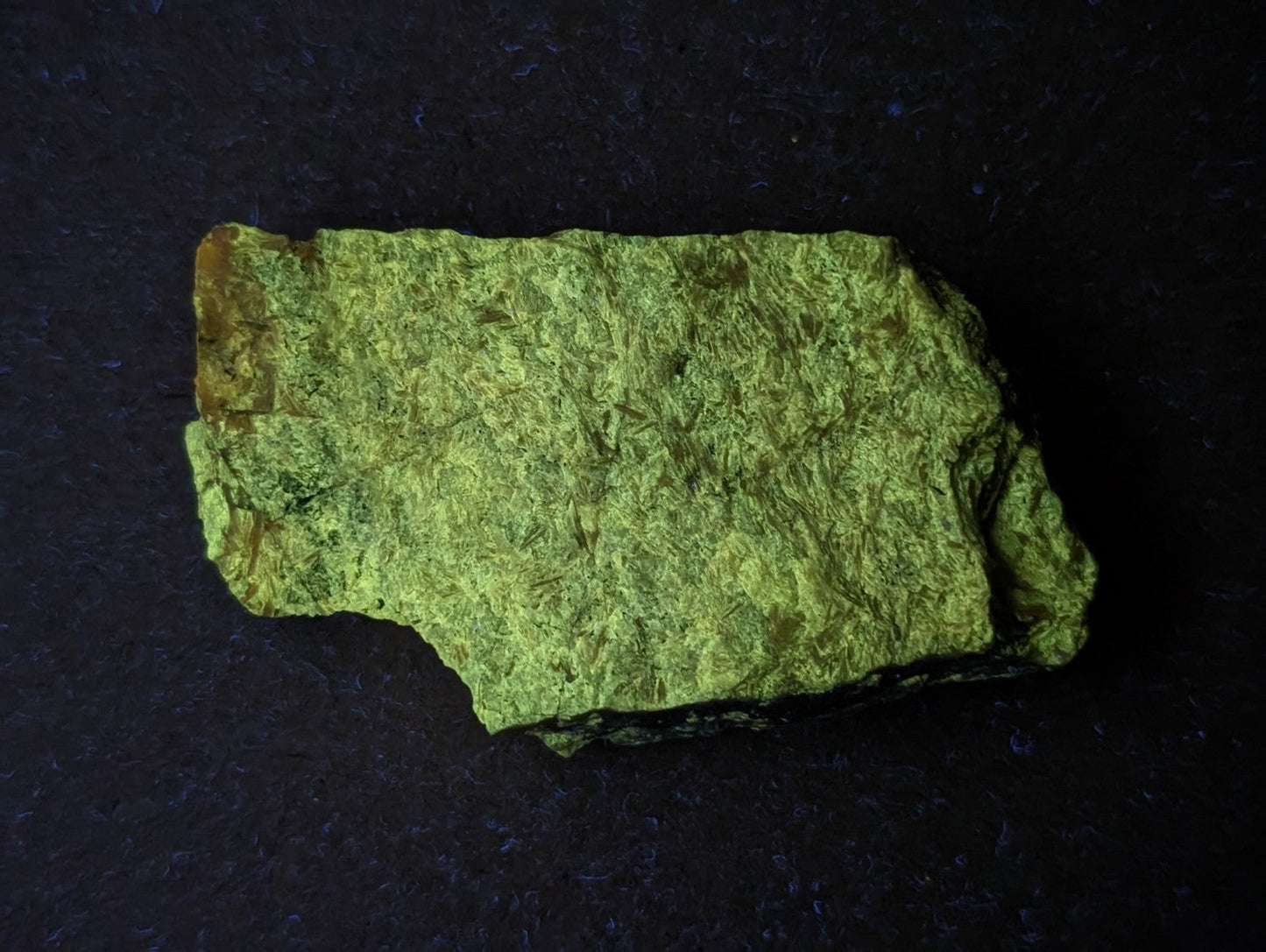 A rough, irregularly shaped piece of green mineral with a textured surface and subtle yellowish-brown edges.
