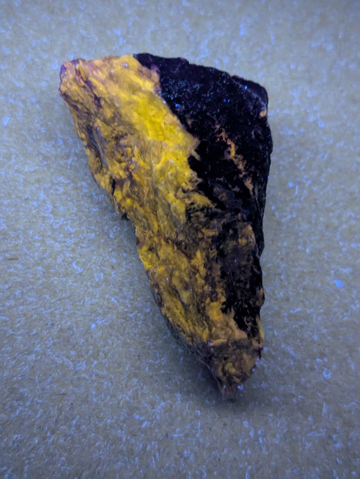 A rugged, irregularly shaped mineral specimen with a striking contrast of vibrant yellow and deep black patches.