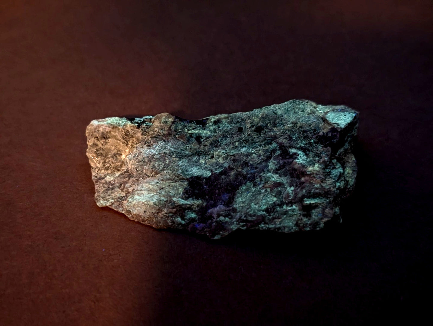 A rugged, irregularly shaped piece of weathered metal with a mottled green and dark gray patina.