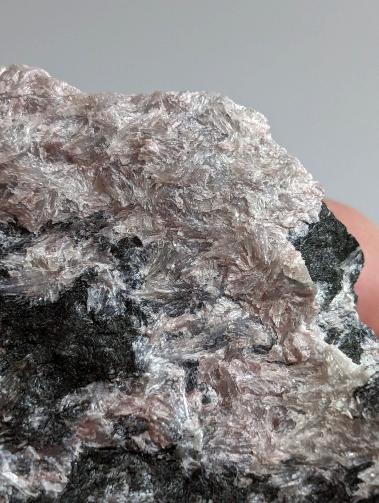A rough, crystalline mineral specimen with a mix of translucent silver and dark gray patches.