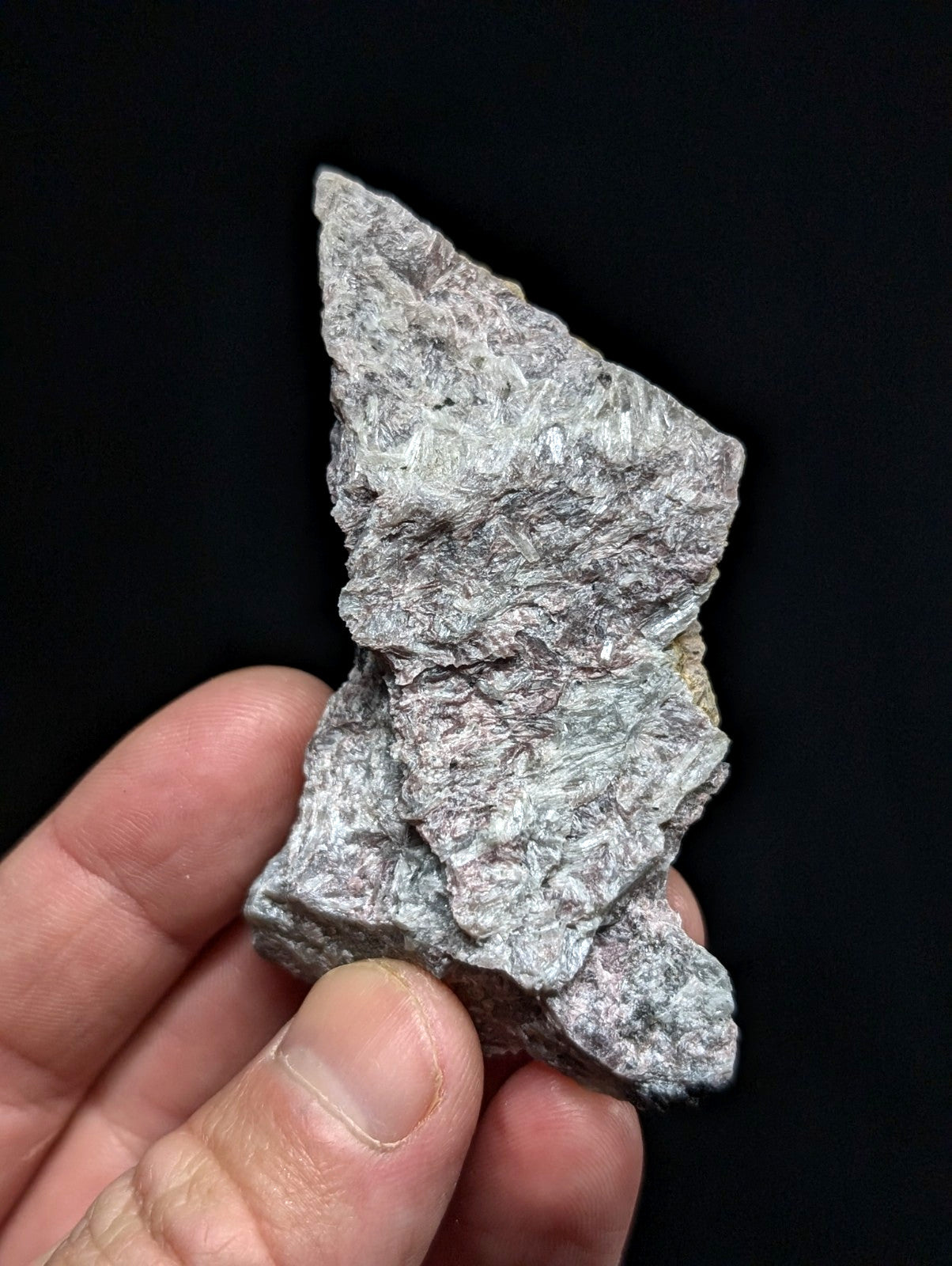 A rough, irregularly shaped gray rock with a textured surface and subtle greenish undertones.