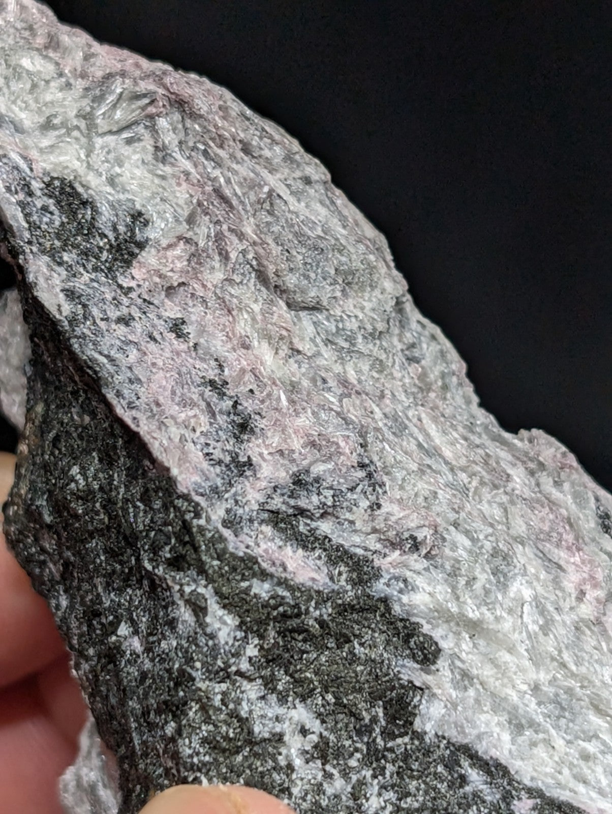 A rugged, naturally occurring rock specimen with a textured surface displaying patches of gray, white, and subtle pinkish hues.