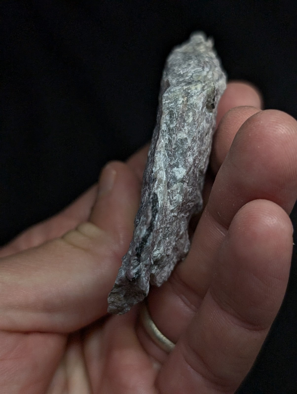 A rough, irregularly shaped gray rock with a textured surface held in someone’s hand.
