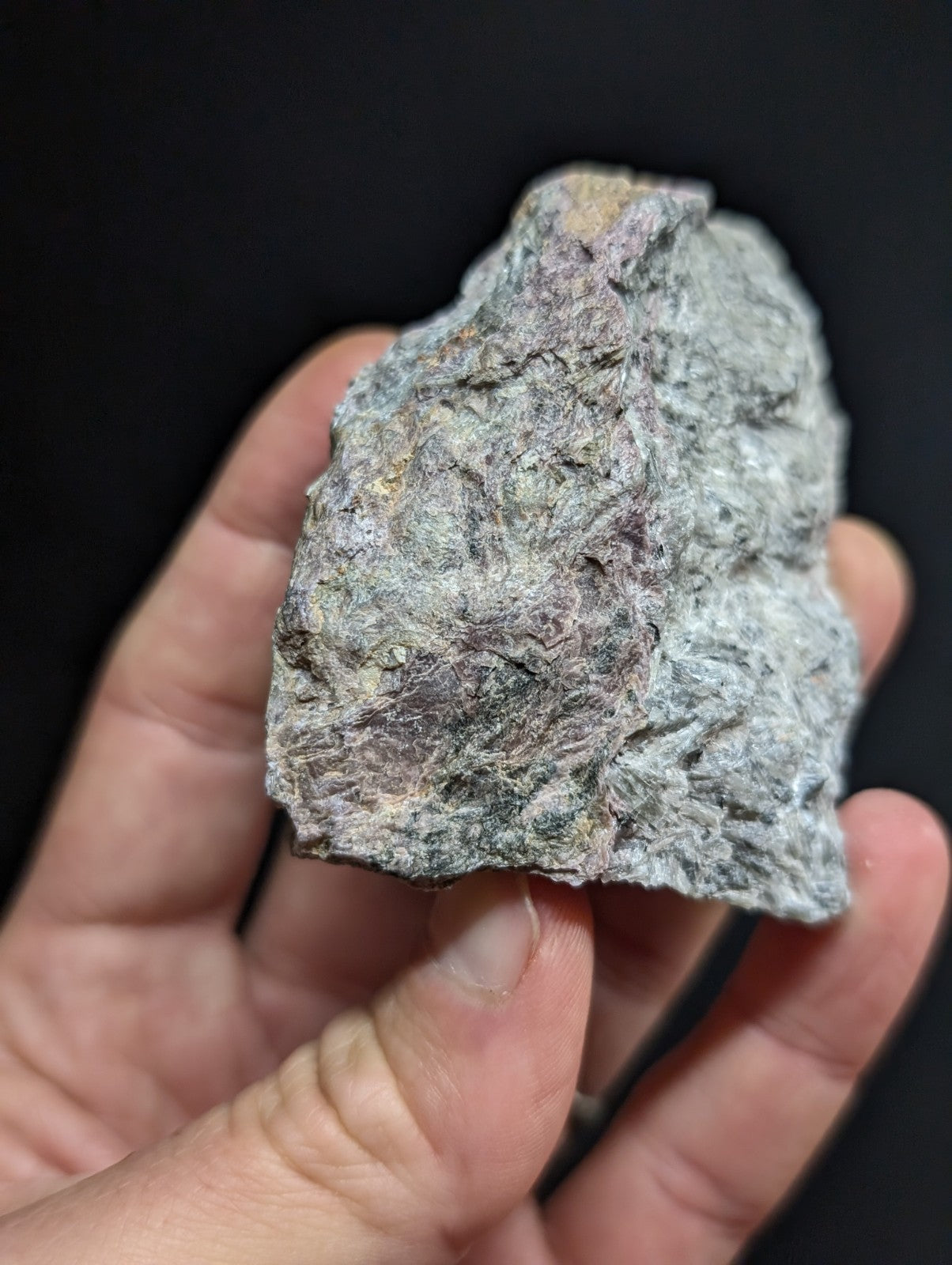 A rough, irregularly shaped rock with a mottled gray and purple surface texture.