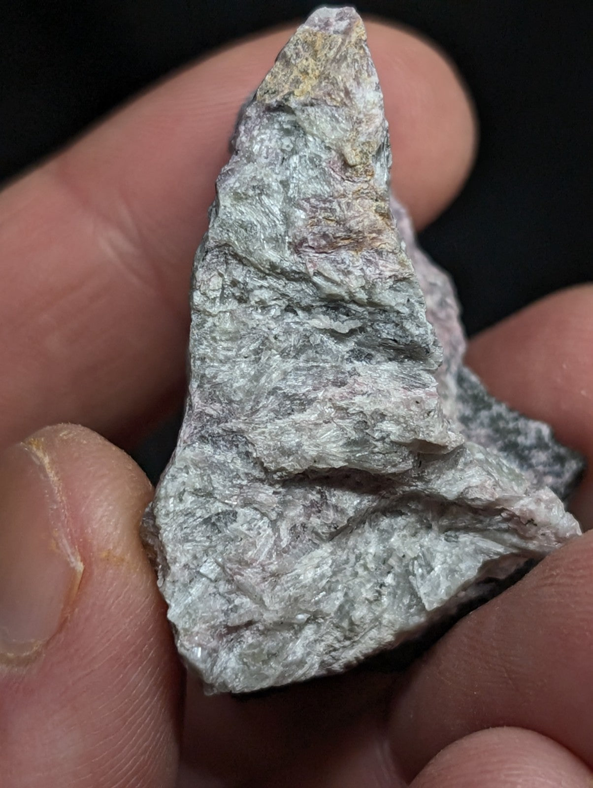 A rough, irregularly shaped gray rock with subtle greenish and whitish veining.