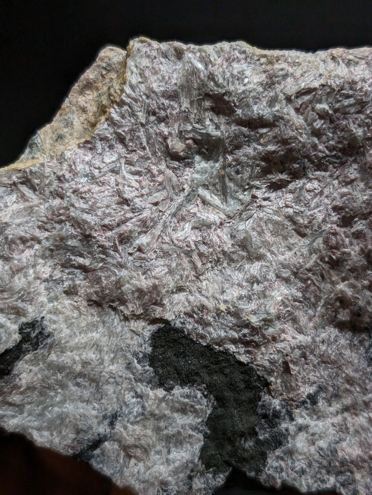 A rough, irregularly shaped mineral specimen with a silvery-gray surface and embedded dark patches.