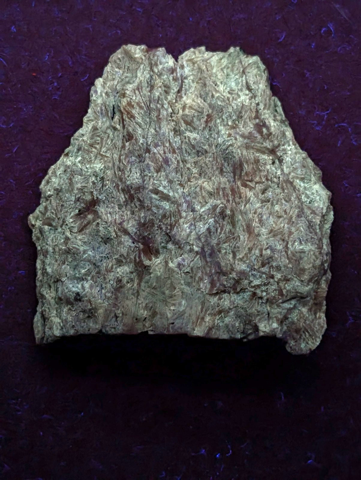 A rough, irregularly shaped piece of greenish-gray mineral with a textured surface and subtle brown streaks.