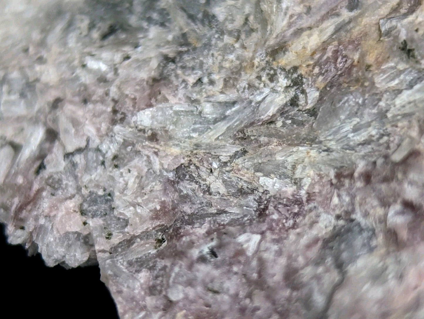 A textured mineral specimen with interwoven translucent crystals in shades of gray, white, and subtle pinkish hues.