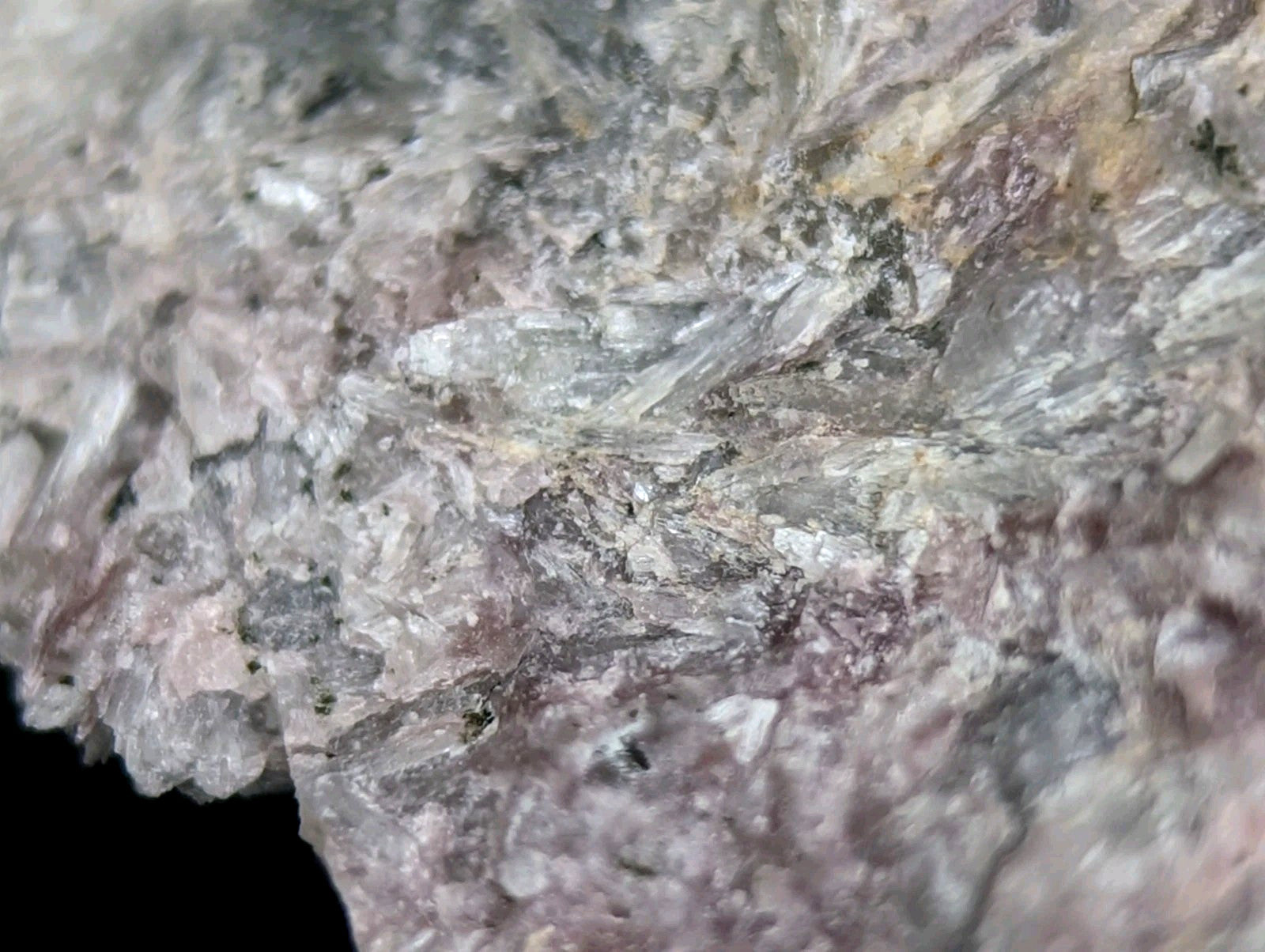 A textured mineral specimen with interwoven translucent crystals in shades of gray, white, and subtle pinkish hues.