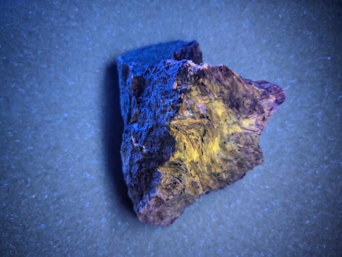 A rugged, irregularly shaped mineral specimen with a striking contrast of deep blue and vibrant yellow-orange hues.