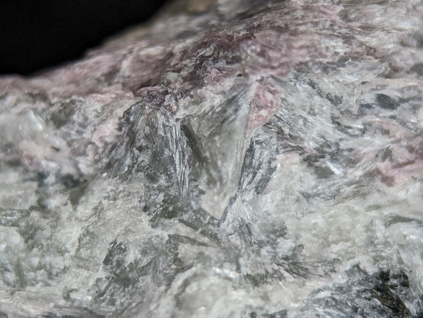 A rugged, naturally occurring rock specimen with a mottled surface of gray and pinkish hues.