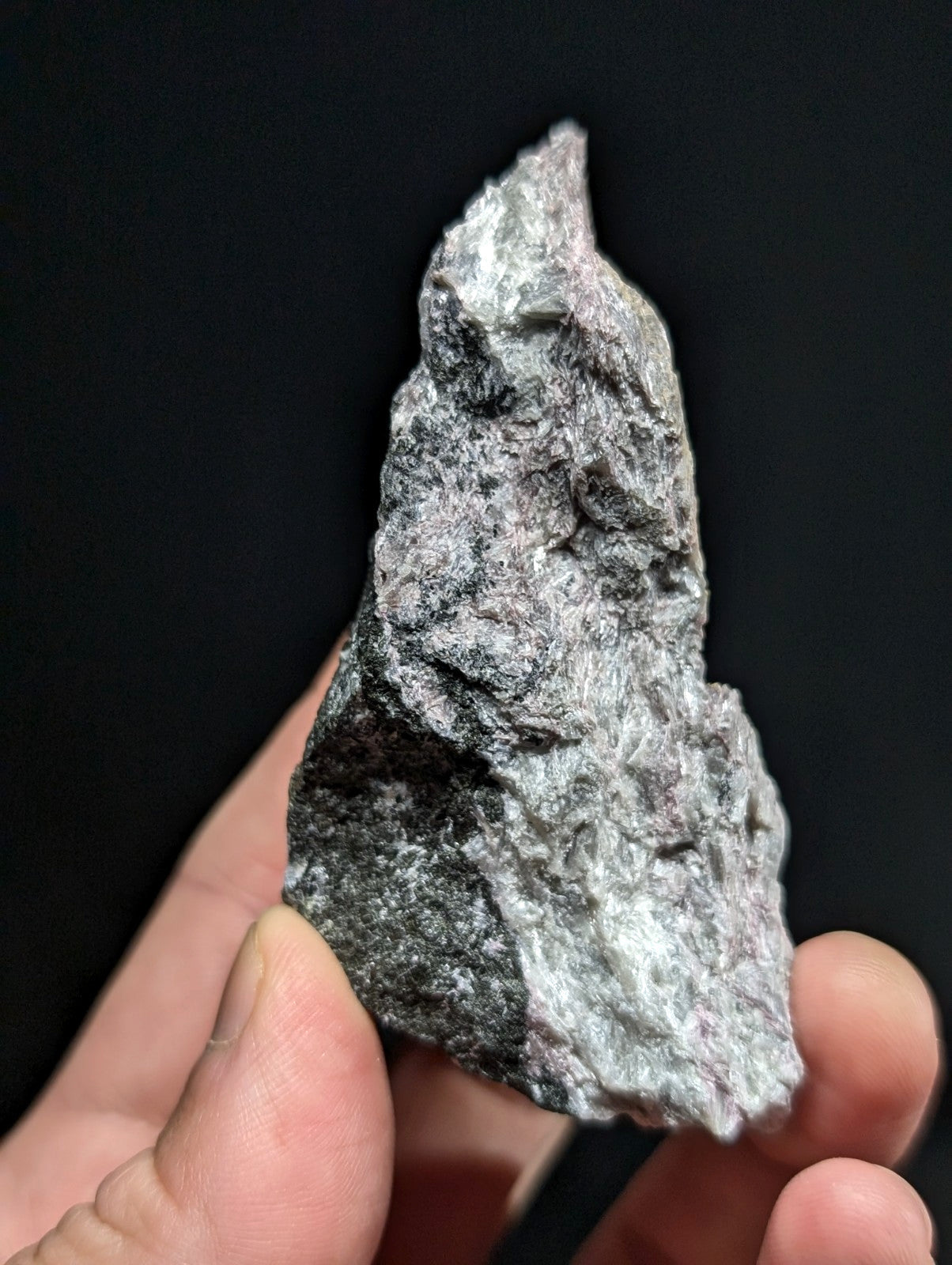 A rough, irregularly shaped gray rock with a textured surface and subtle white veining.