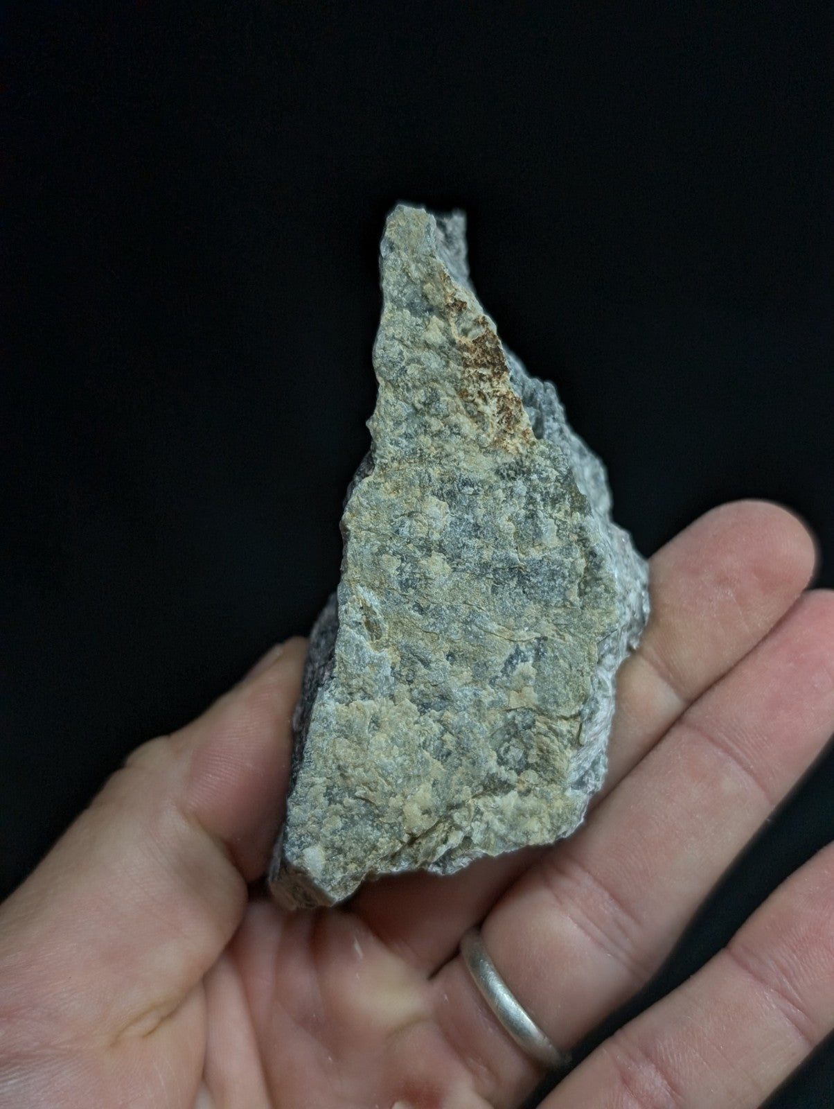A rough, irregularly shaped gray rock fragment with subtle brown and white mineral streaks.
