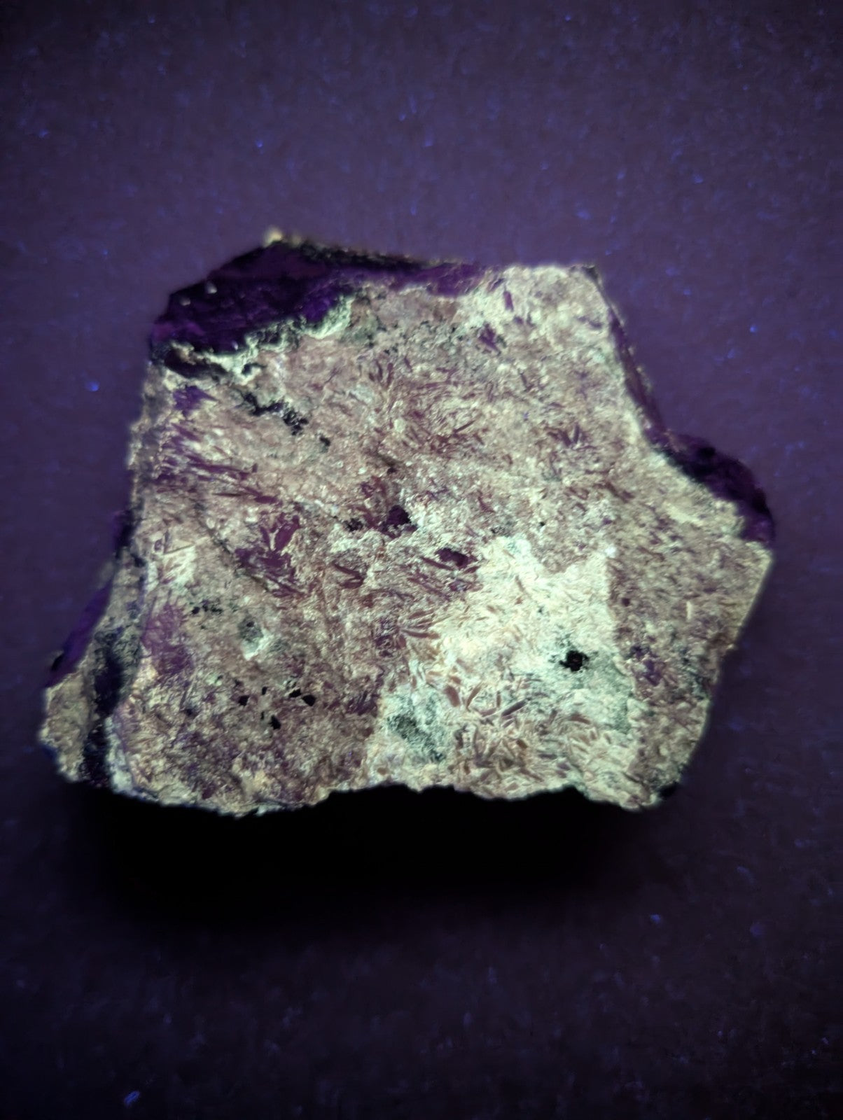 A rough, irregularly shaped piece of purple and gray mineral with a textured surface.