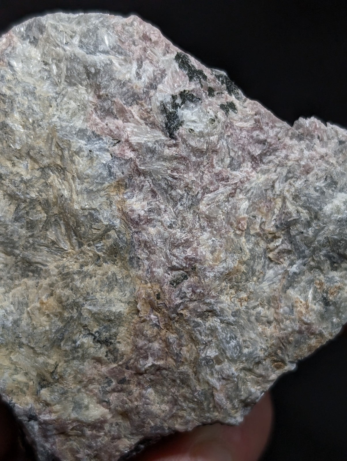 A rough, irregularly shaped rock with a mottled surface of gray, white, and subtle pinkish hues.
