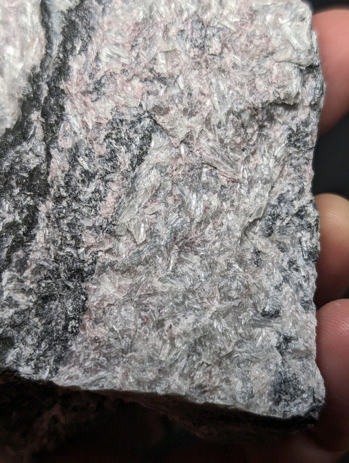 A rough, irregularly shaped rock with a mottled gray and white surface featuring visible crystalline textures.