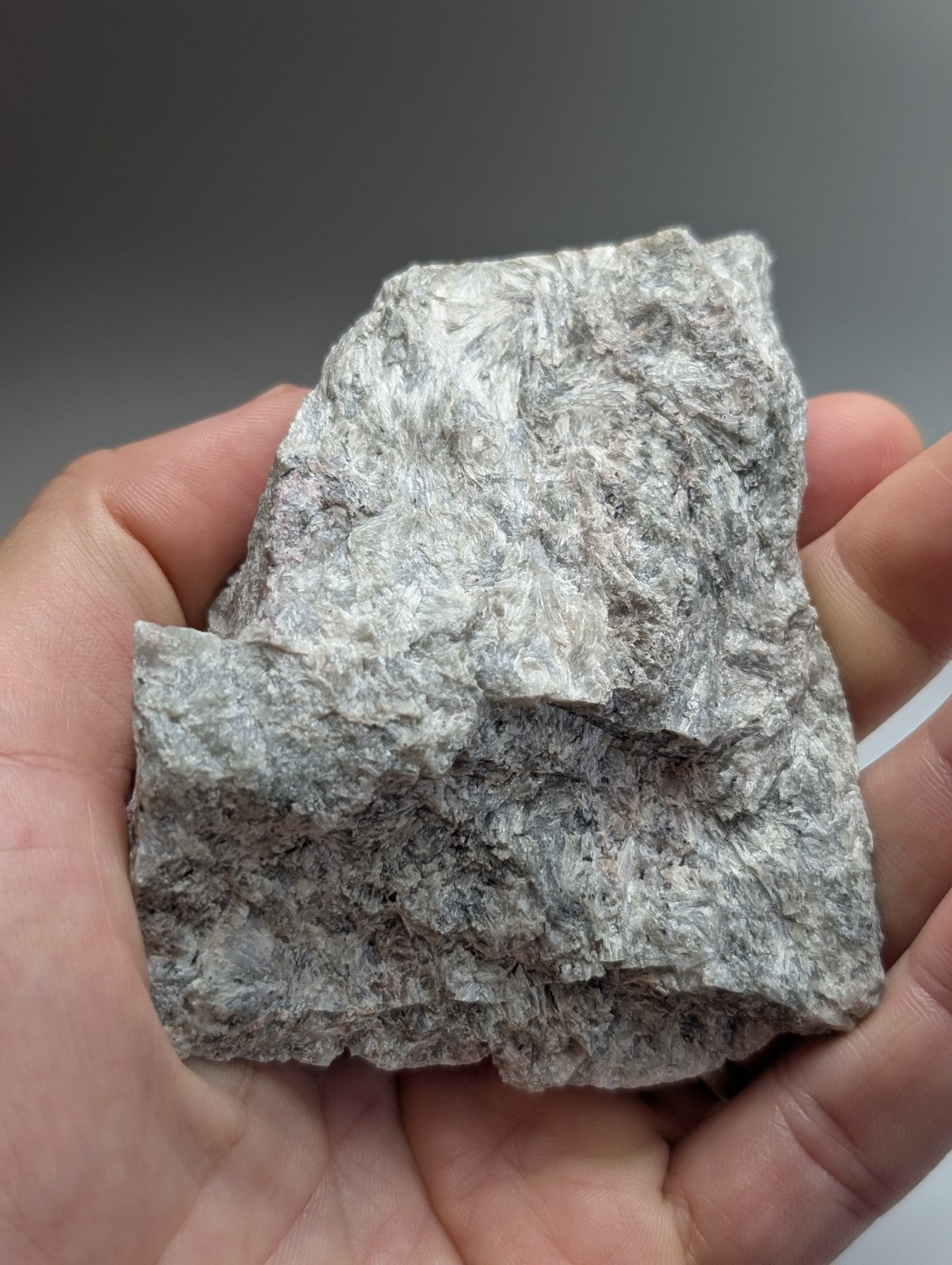 A rough gray miserite and wollastonite mineral specimen with a textured surface held in hand from wilson springs arkansas