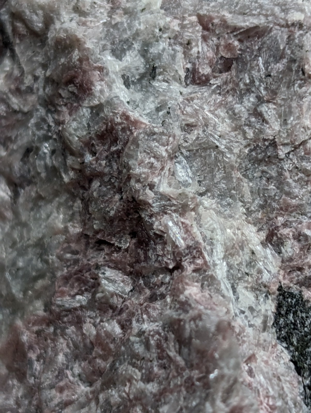 A rough, textured mineral specimen with a mottled pattern of gray and reddish-brown hues.