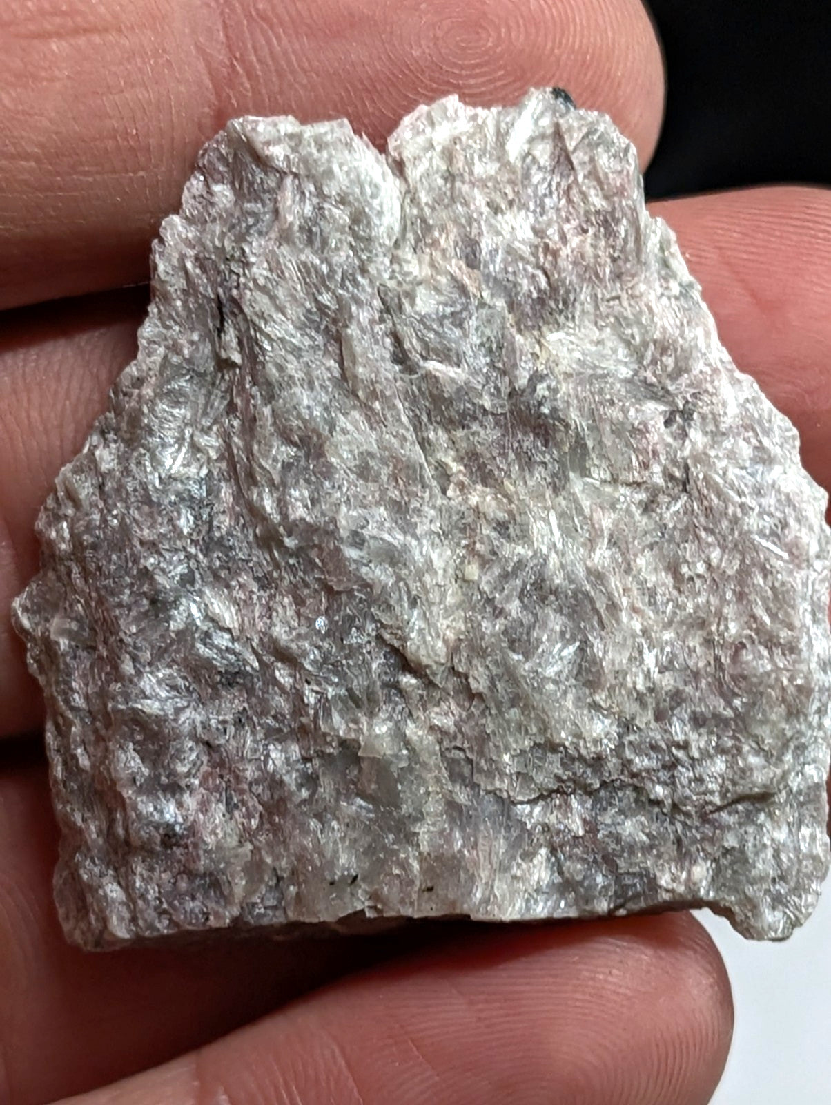 A rough, silver-colored metallic mineral specimen with a crystalline texture and irregular edges.