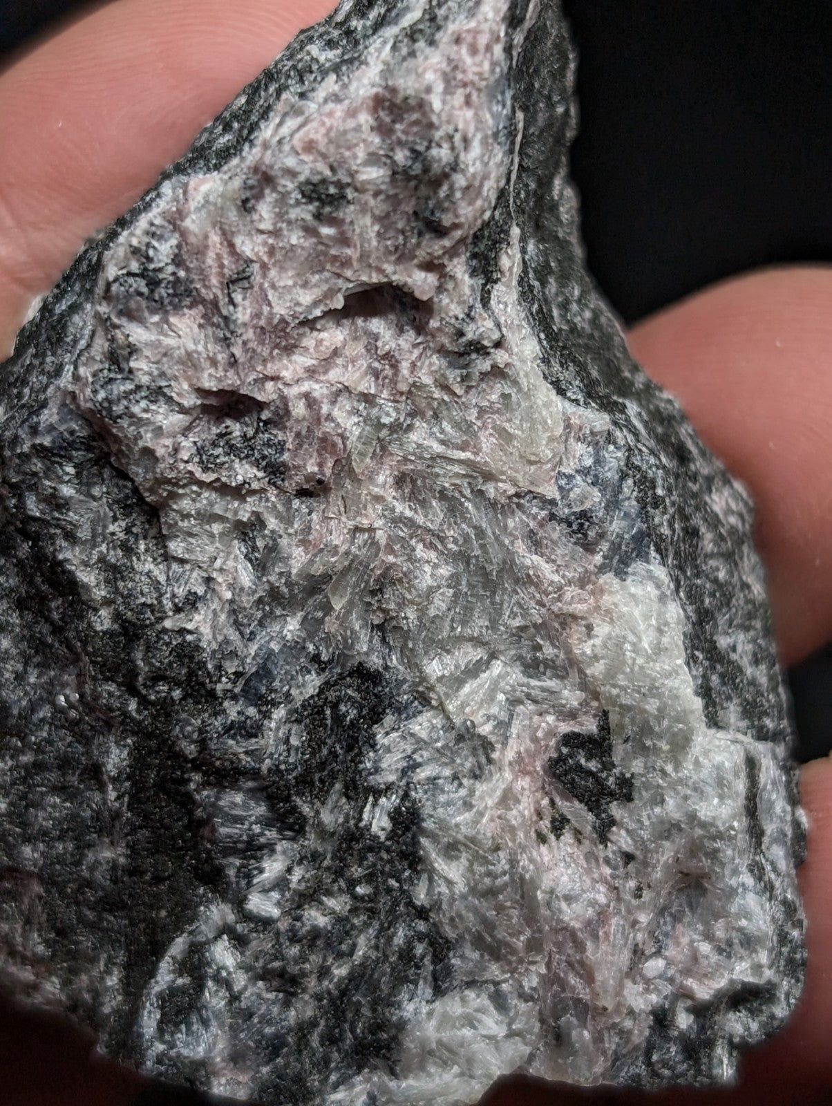 A rugged, naturally occurring rock with a mottled pattern of dark gray and light pinkish-white mineral veins.