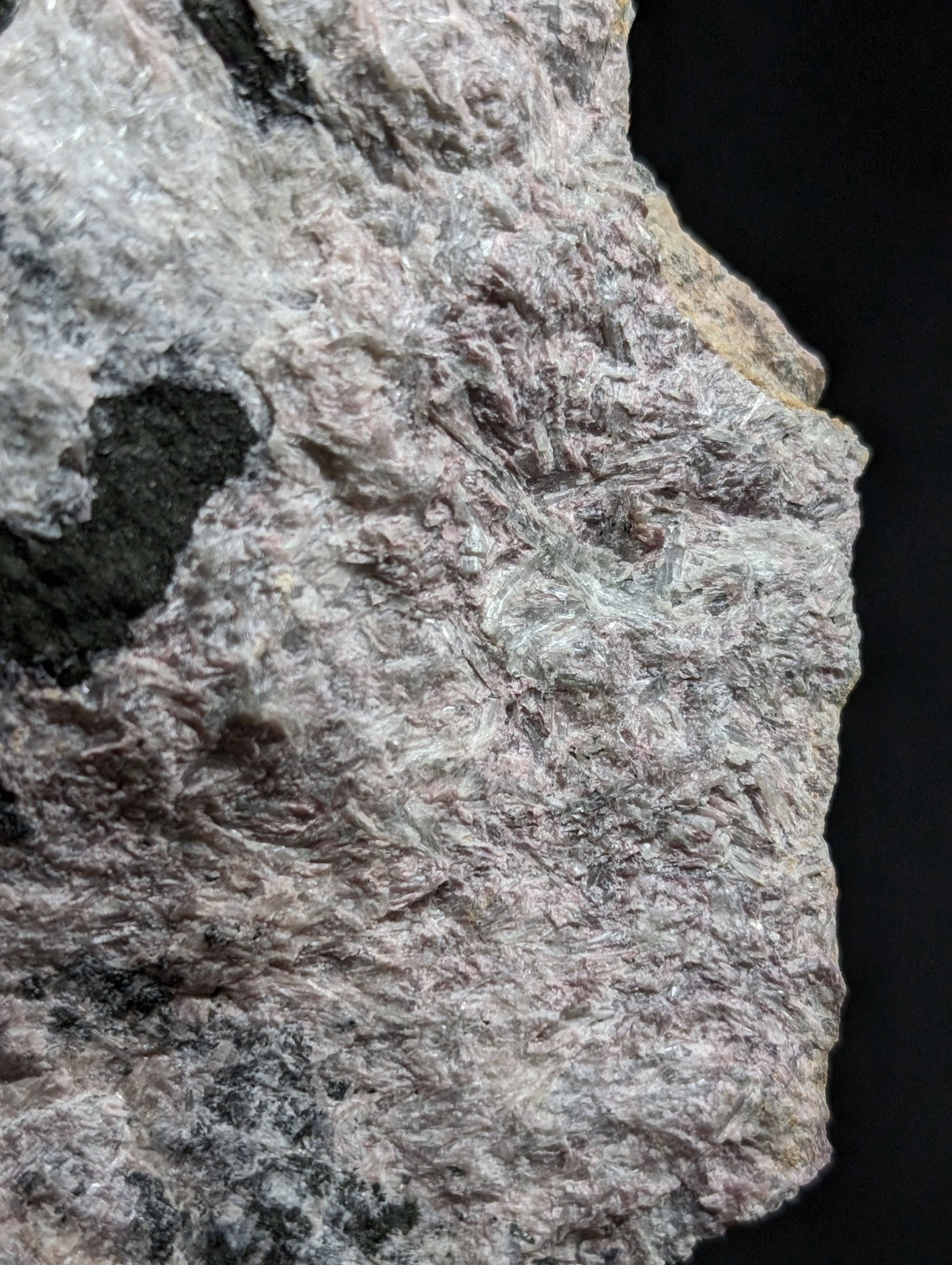 A rough, textured mineral specimen with a mottled gray and white surface featuring subtle greenish veining.