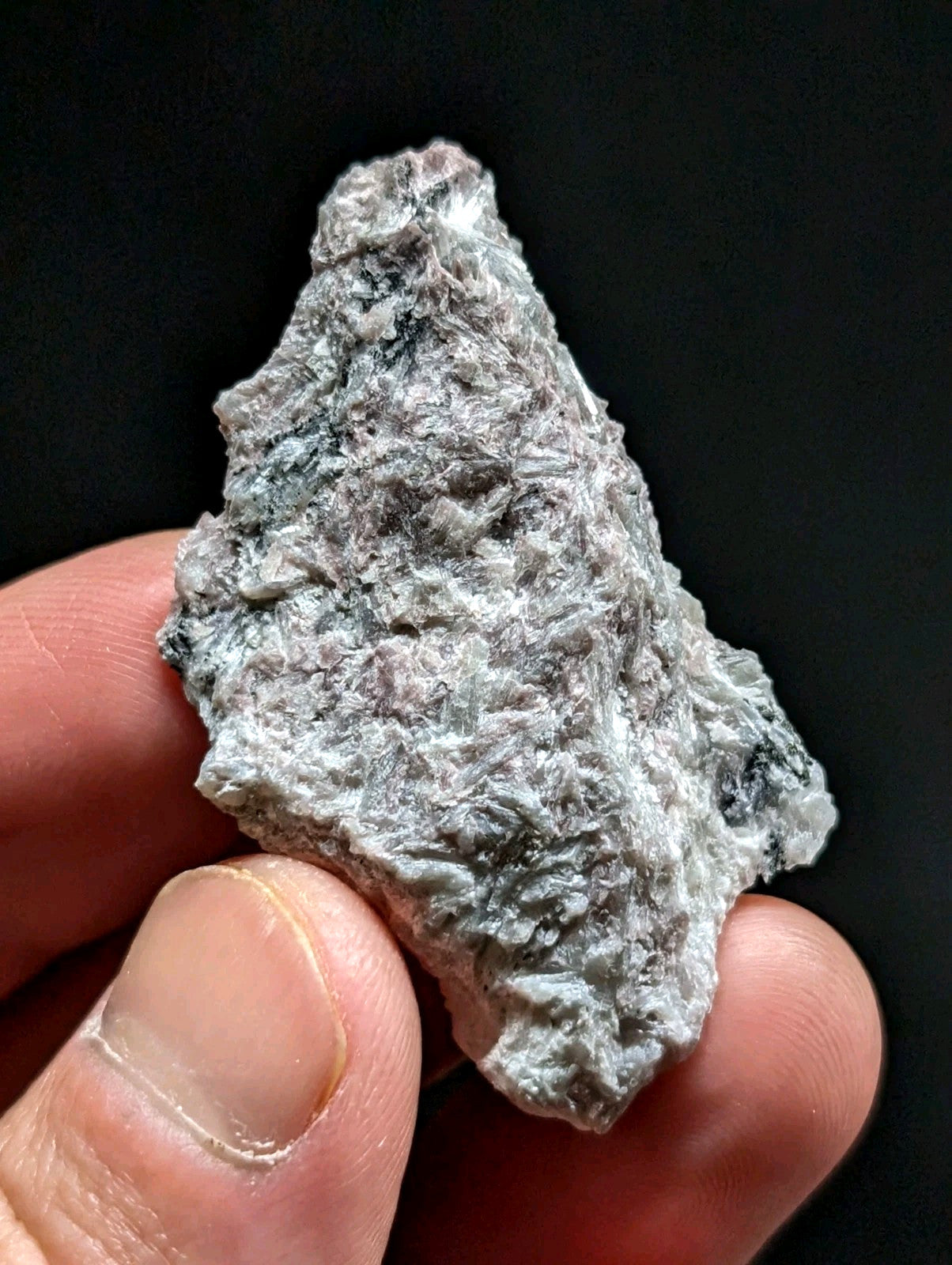 A rough, irregularly shaped piece of grayish-white mineral with subtle dark veining and a textured surface.