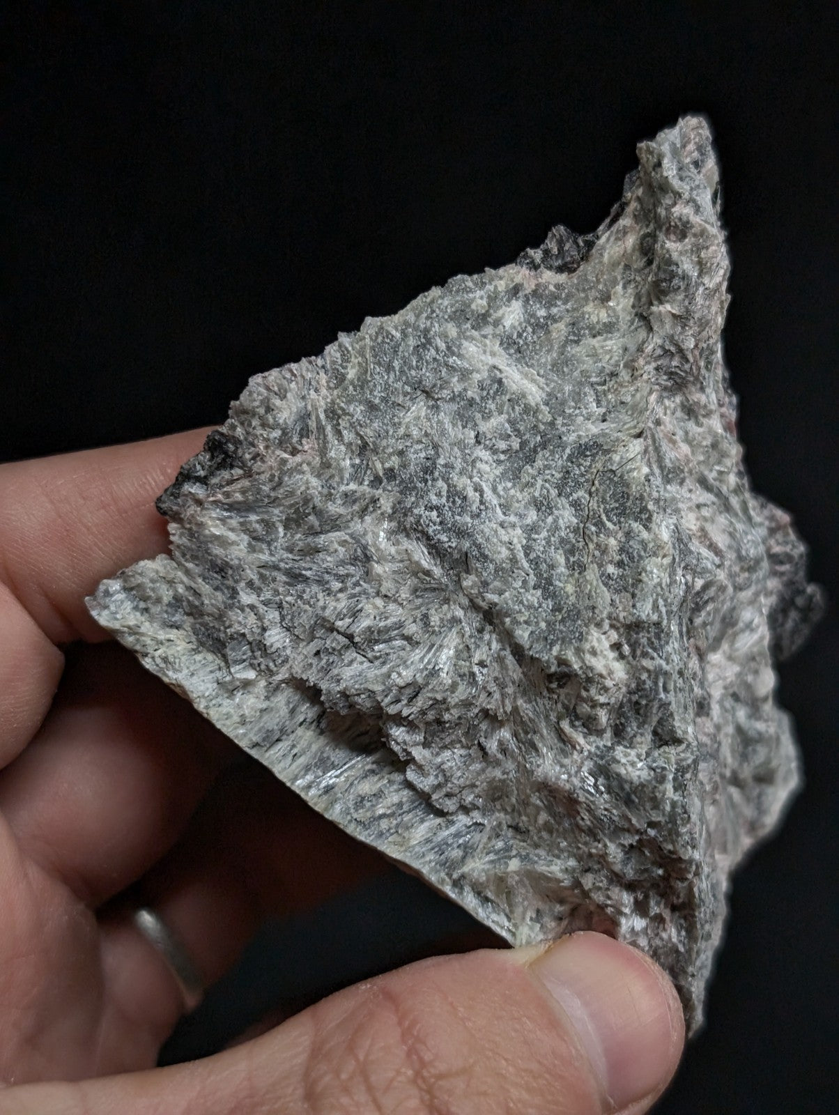 A rough, triangular piece of grayish-white rock with a textured, crystalline surface.