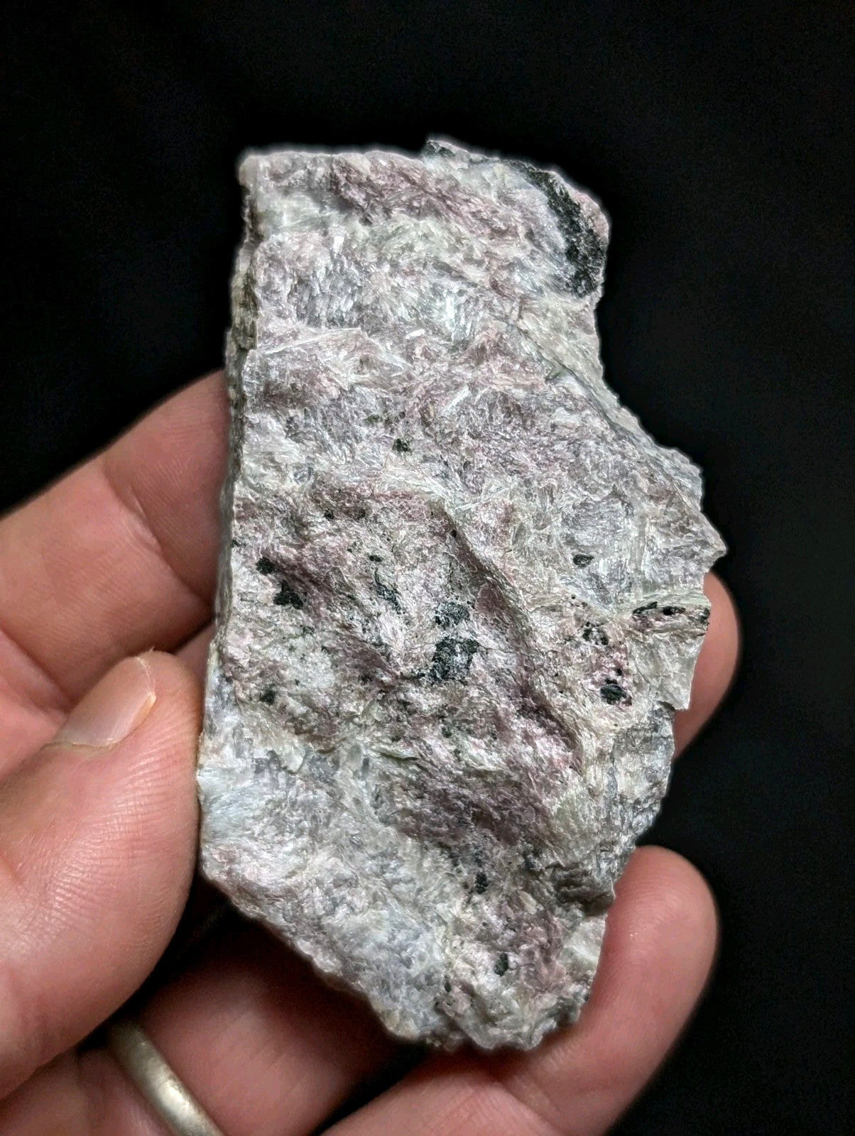 A rough, irregularly shaped piece of grayish-white rock with speckles of darker minerals and a textured surface.