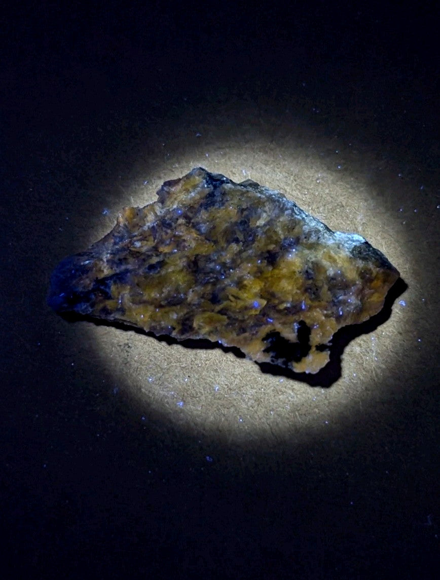 A rugged, irregularly shaped piece of mineral with a mottled surface displaying patches of deep blue and vibrant yellow-orange hues.