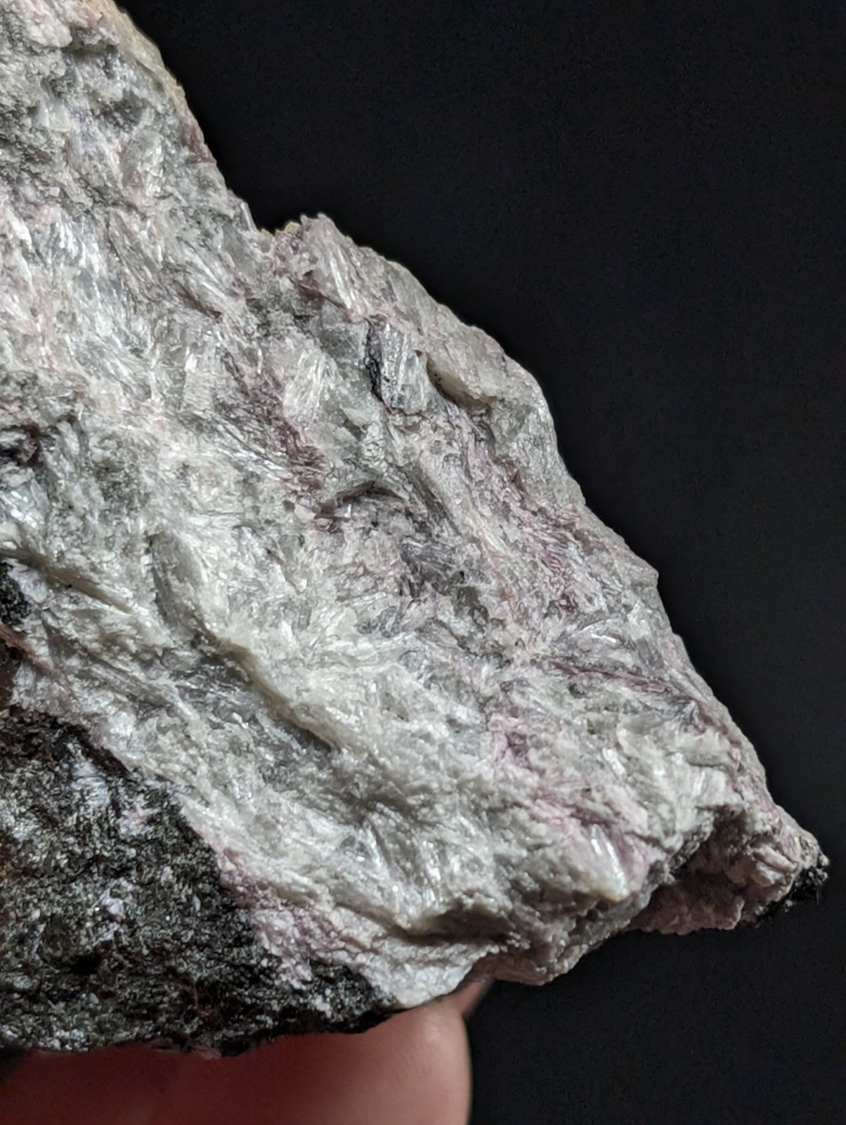 A rough, irregularly shaped mineral specimen with a silvery-white surface and subtle pinkish-purple veining.