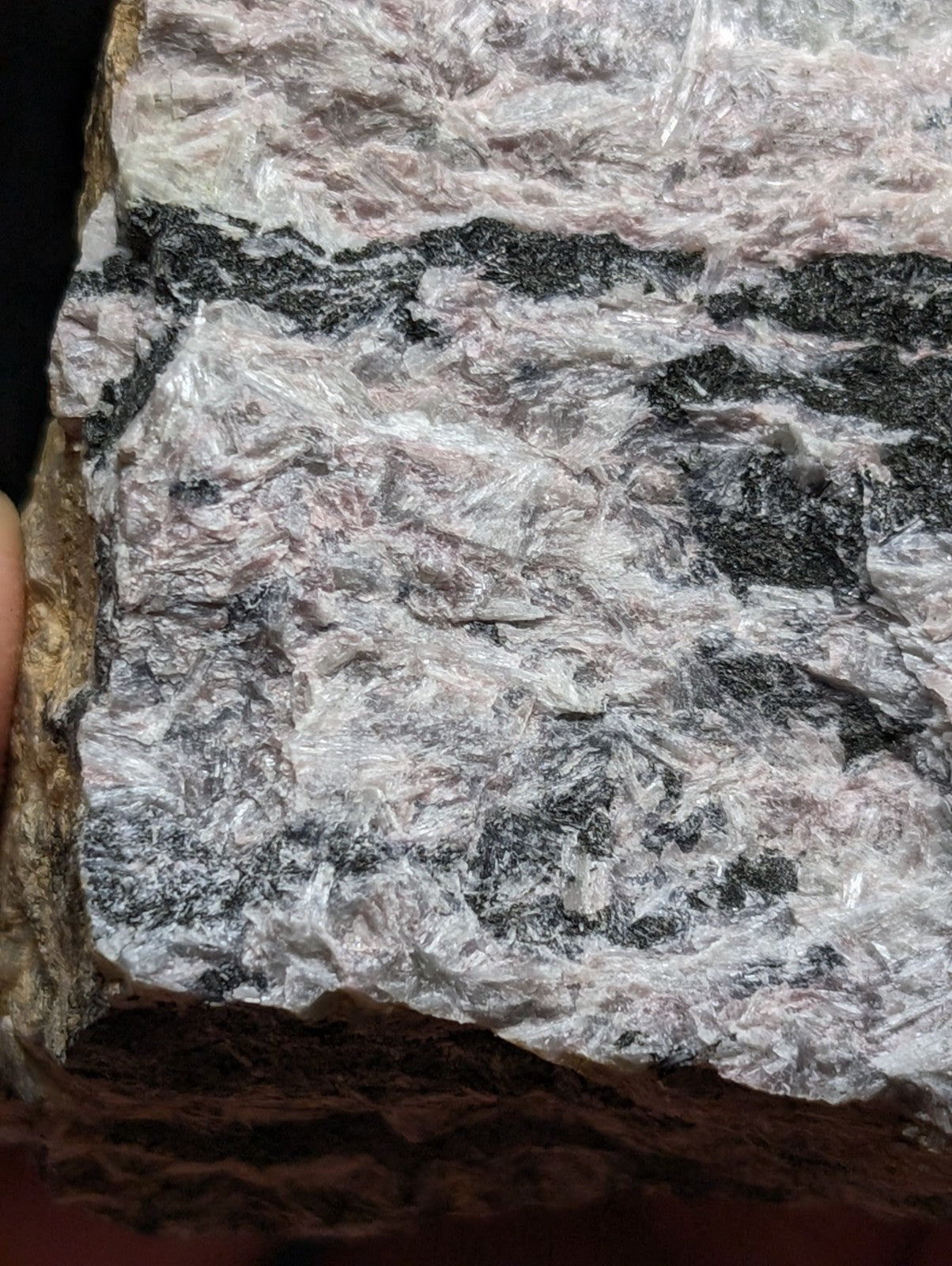 A rugged, naturally occurring rock specimen with a striking pattern of translucent white and gray crystalline formations interwoven with dark black bands.
